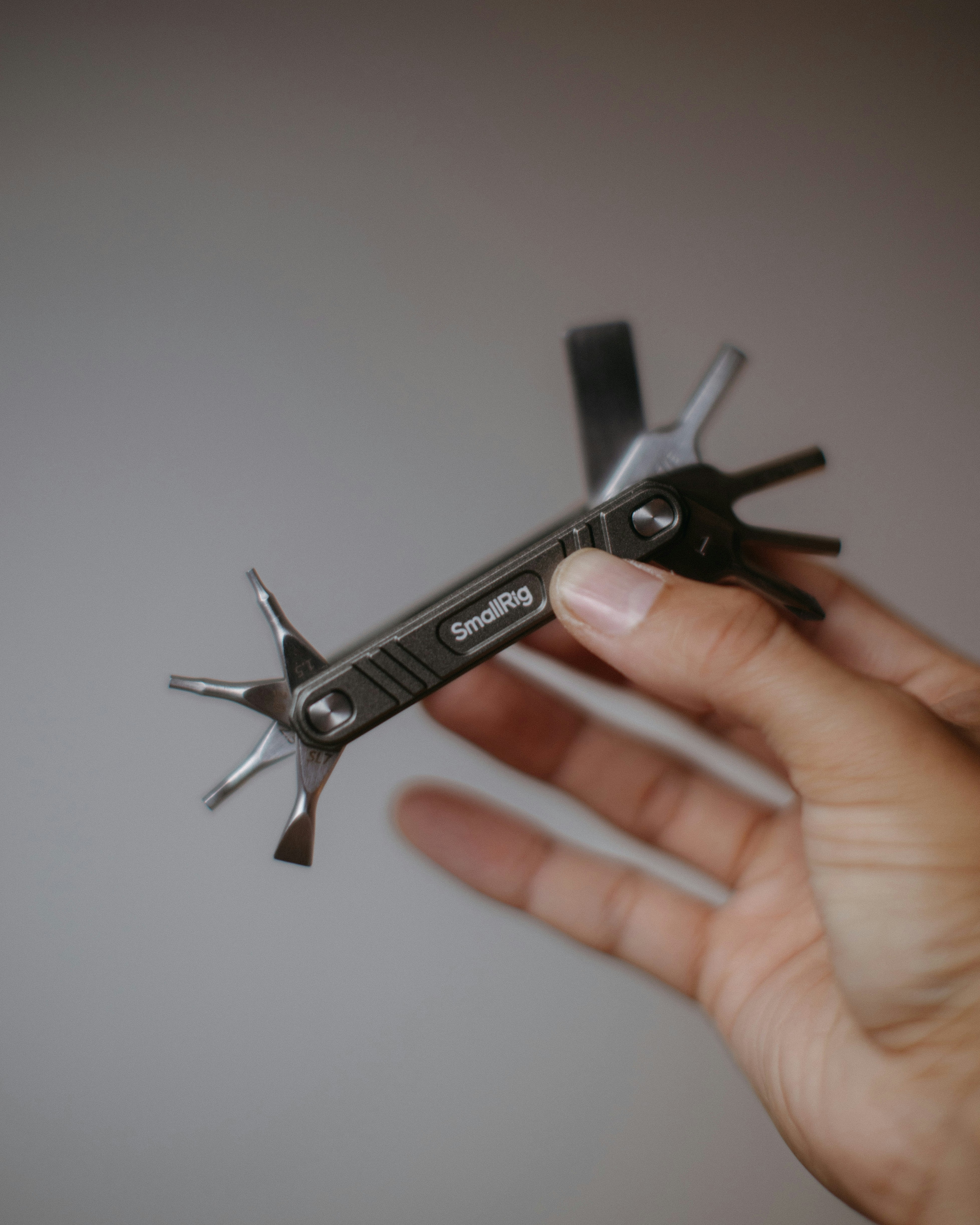 Hand holding a small multi-tool with various attachments.