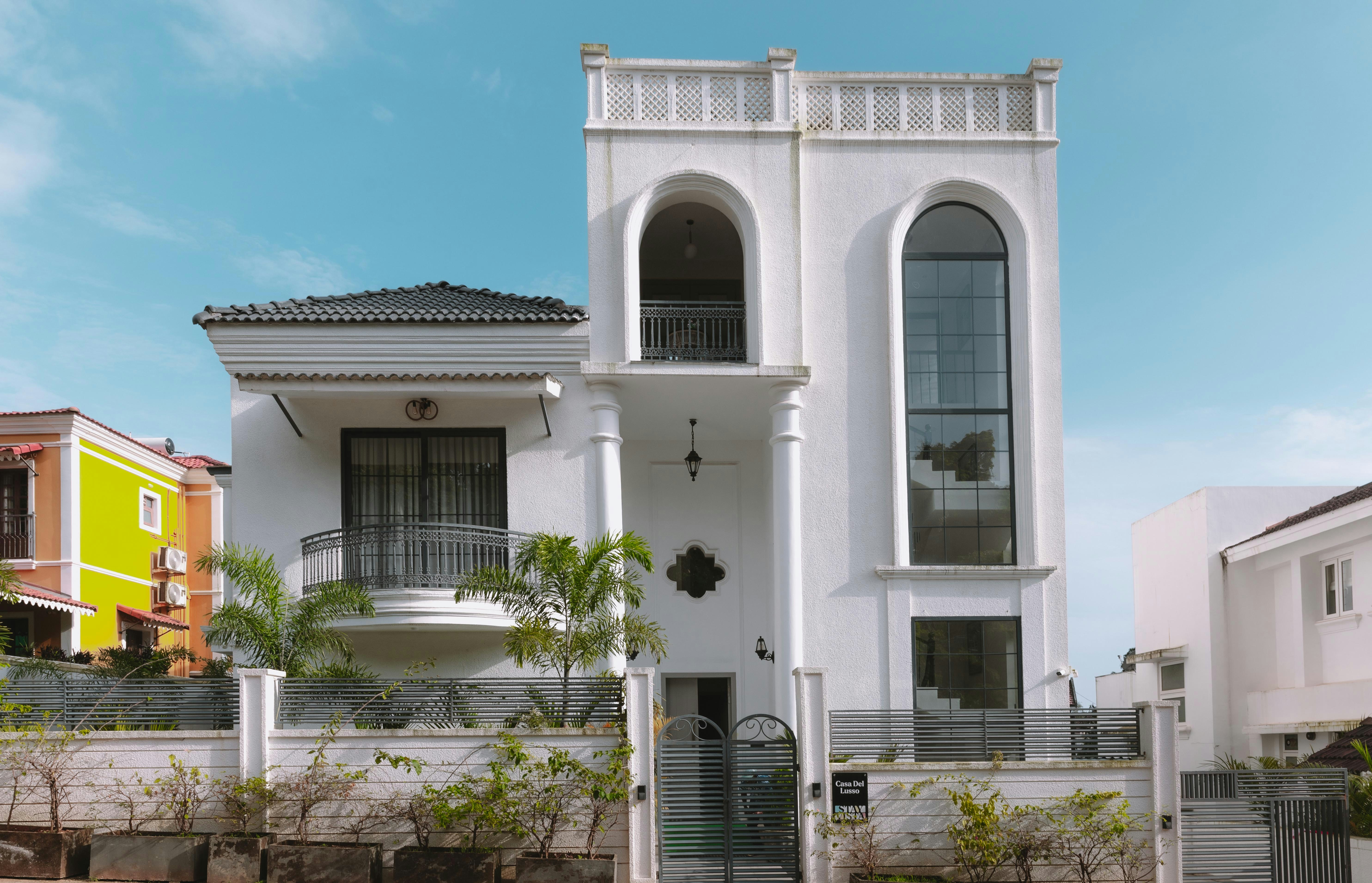 Casa branca moderna com janelas arqueadas e varanda.