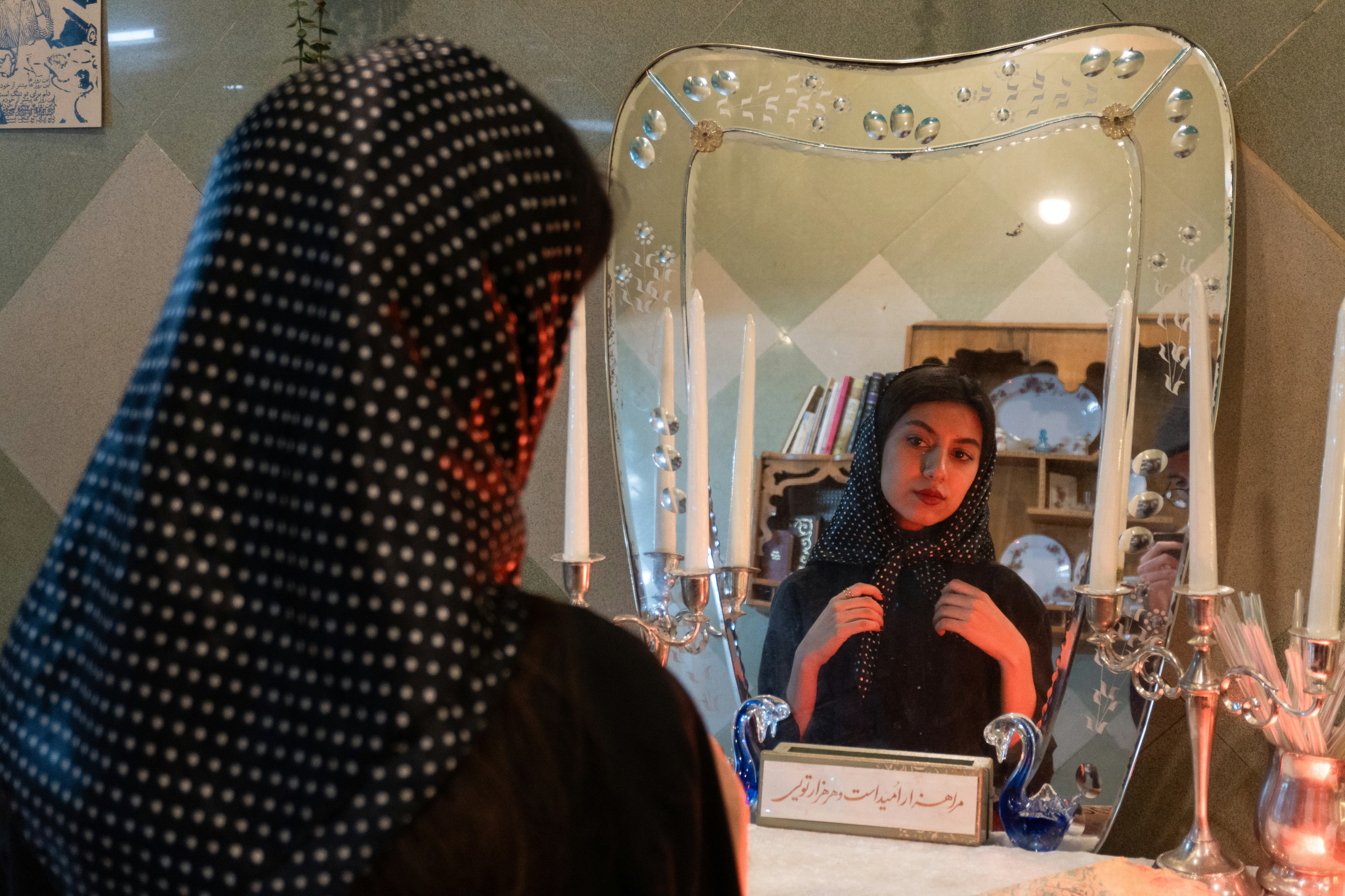 Woman adjusting hijab in front of ornate mirror