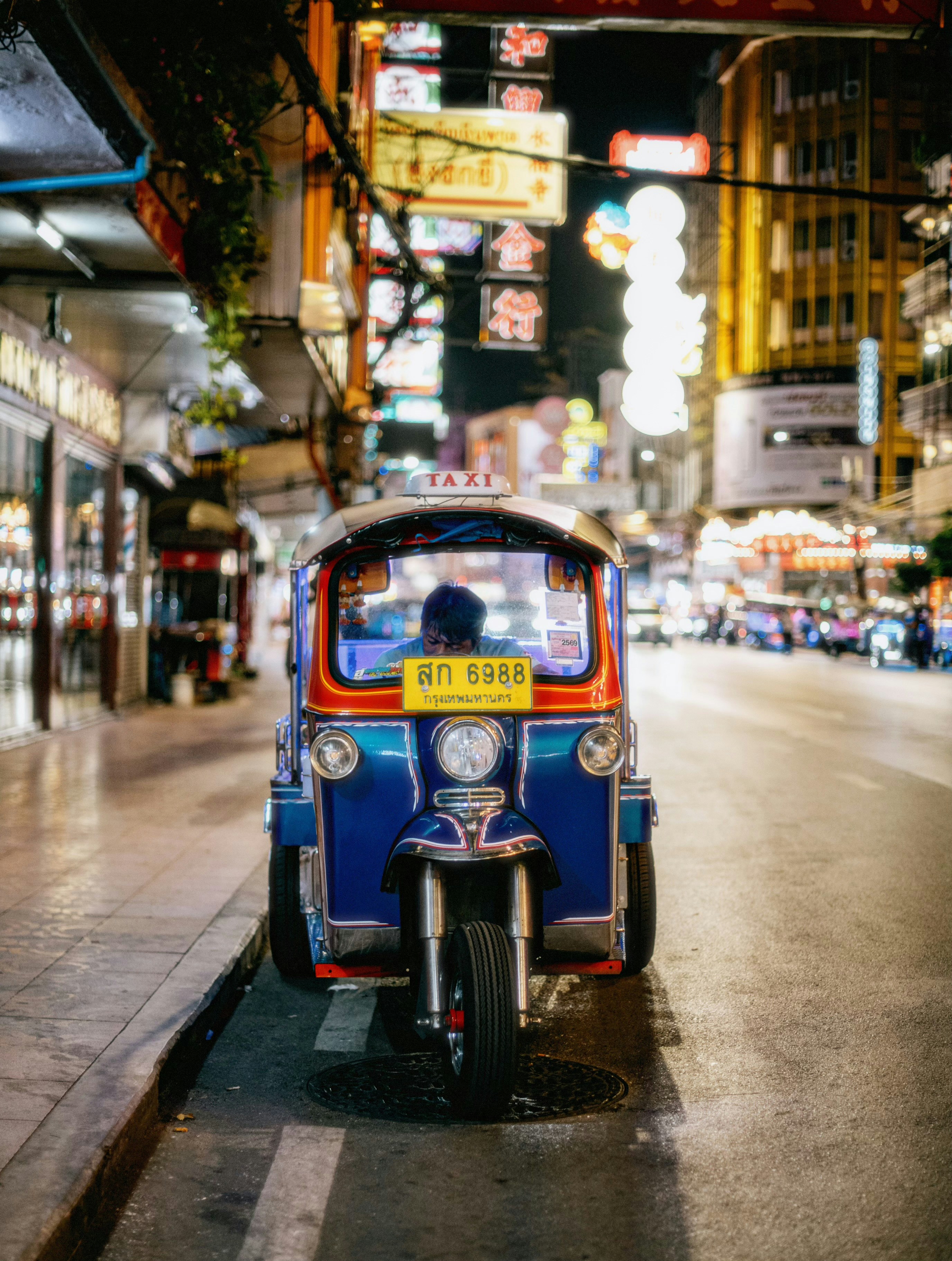 Tuk-tuk parked on a vibrant city street at night