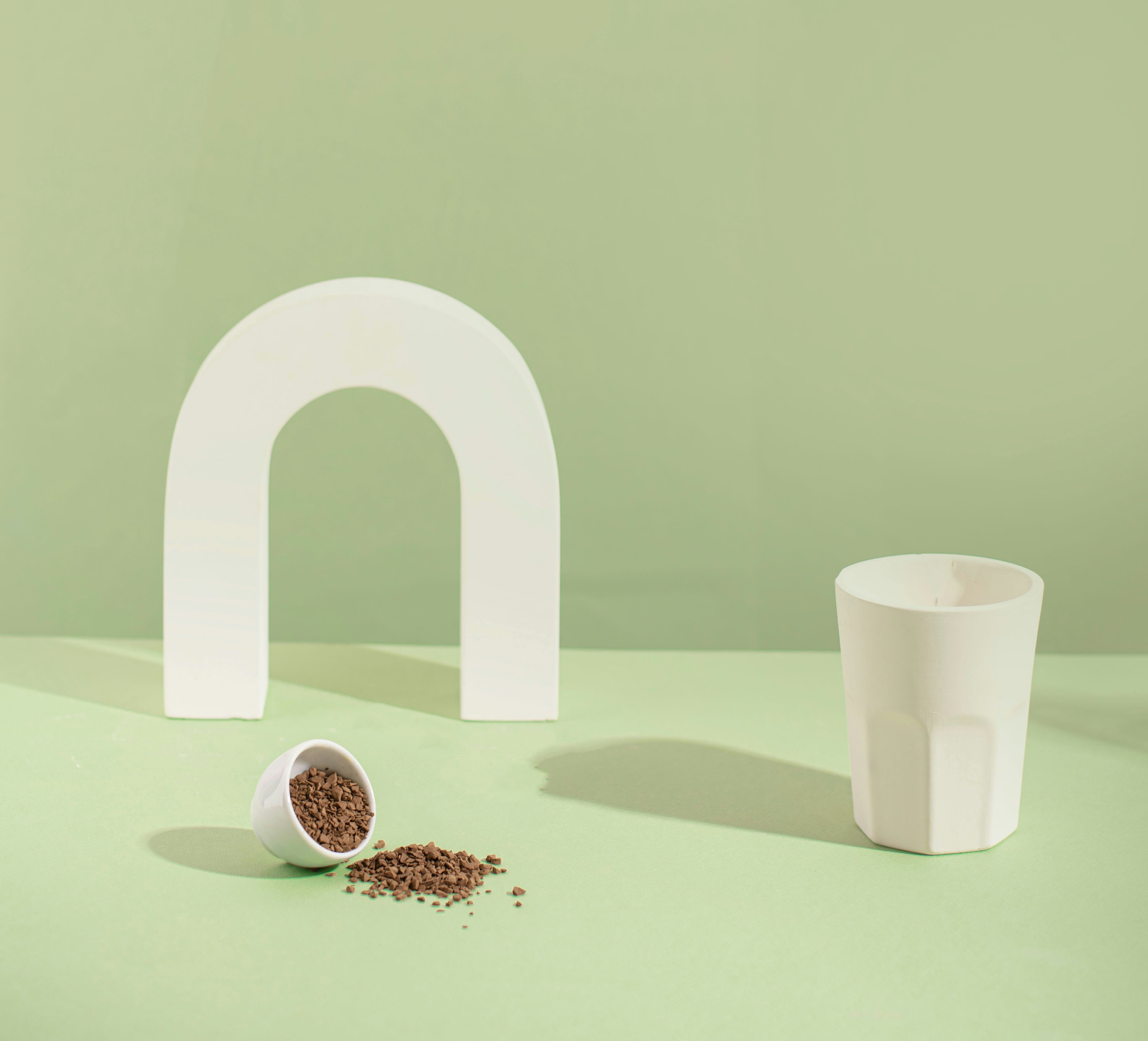 White geometric arch, cup, and spilled coffee grounds