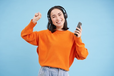 Young woman with headphones and phone dancing happily