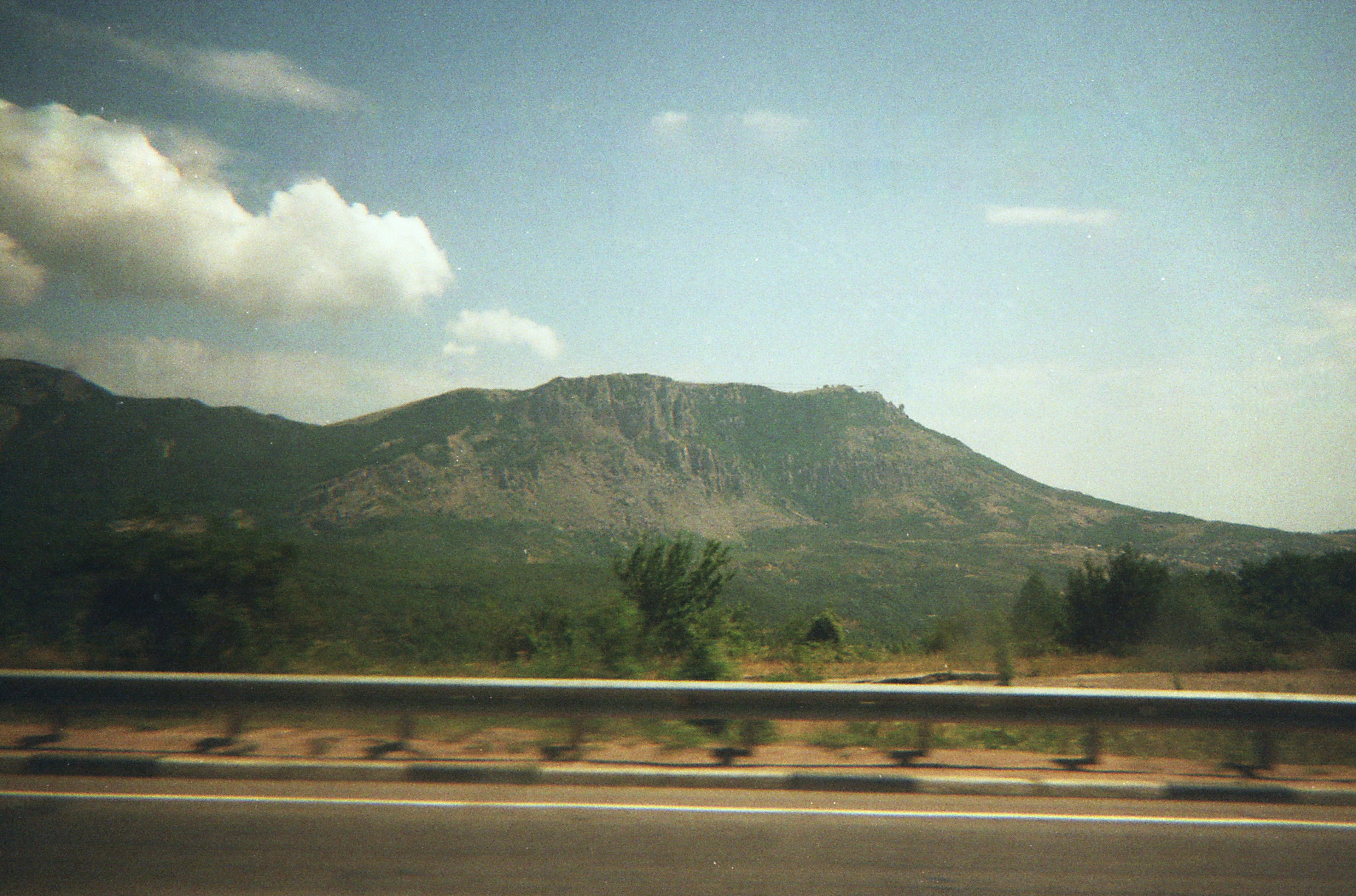 A large mountain range with green trees below.