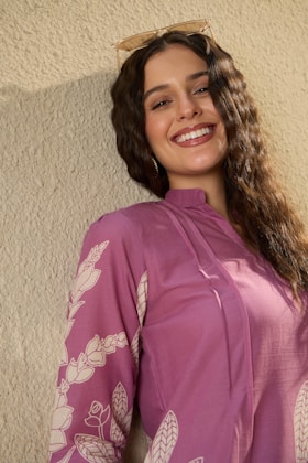 A smiling woman in a purple floral outfit