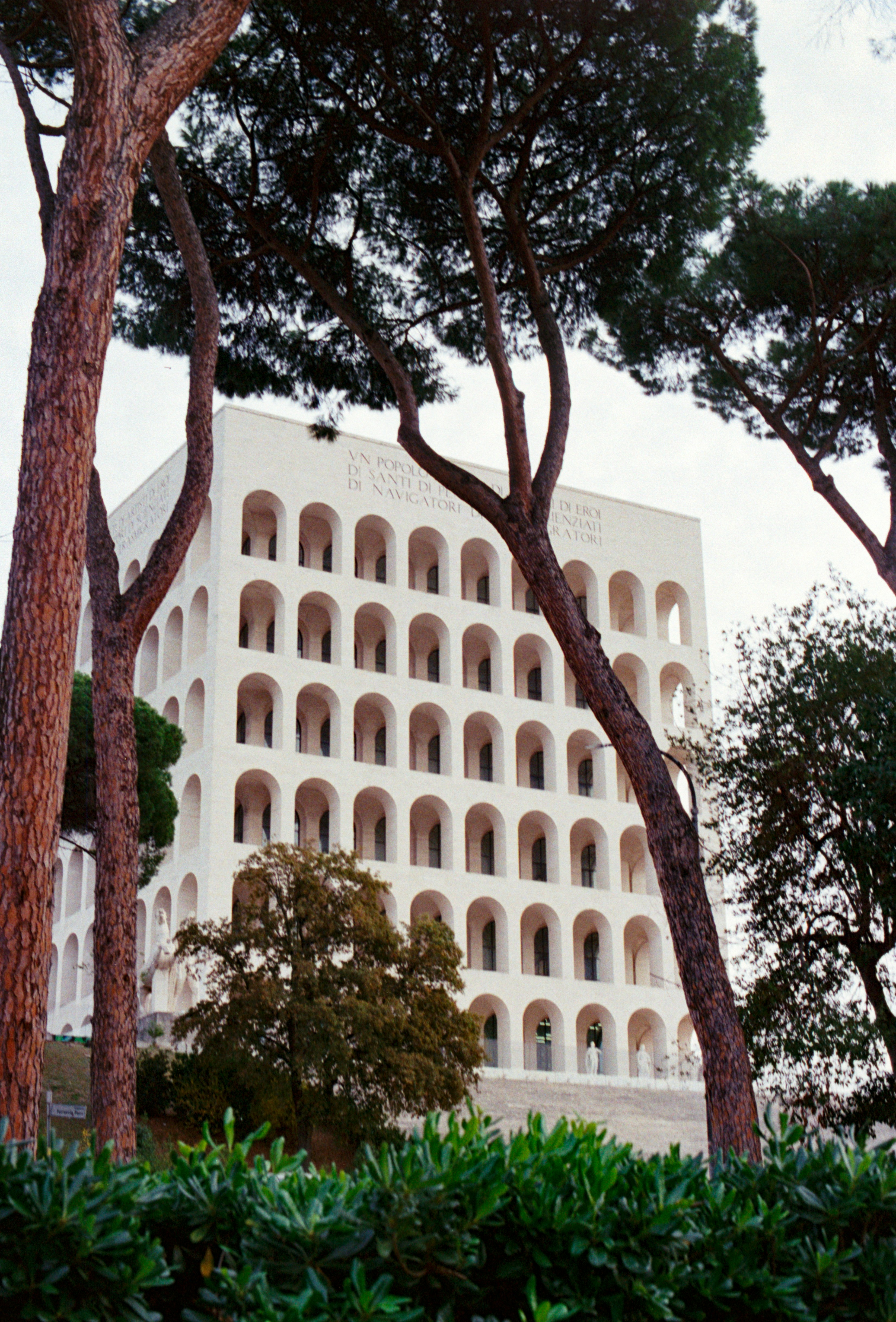 White building with many arched windows framed by trees