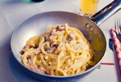 Spaghetti carbonara served in a metal pan with cheese.