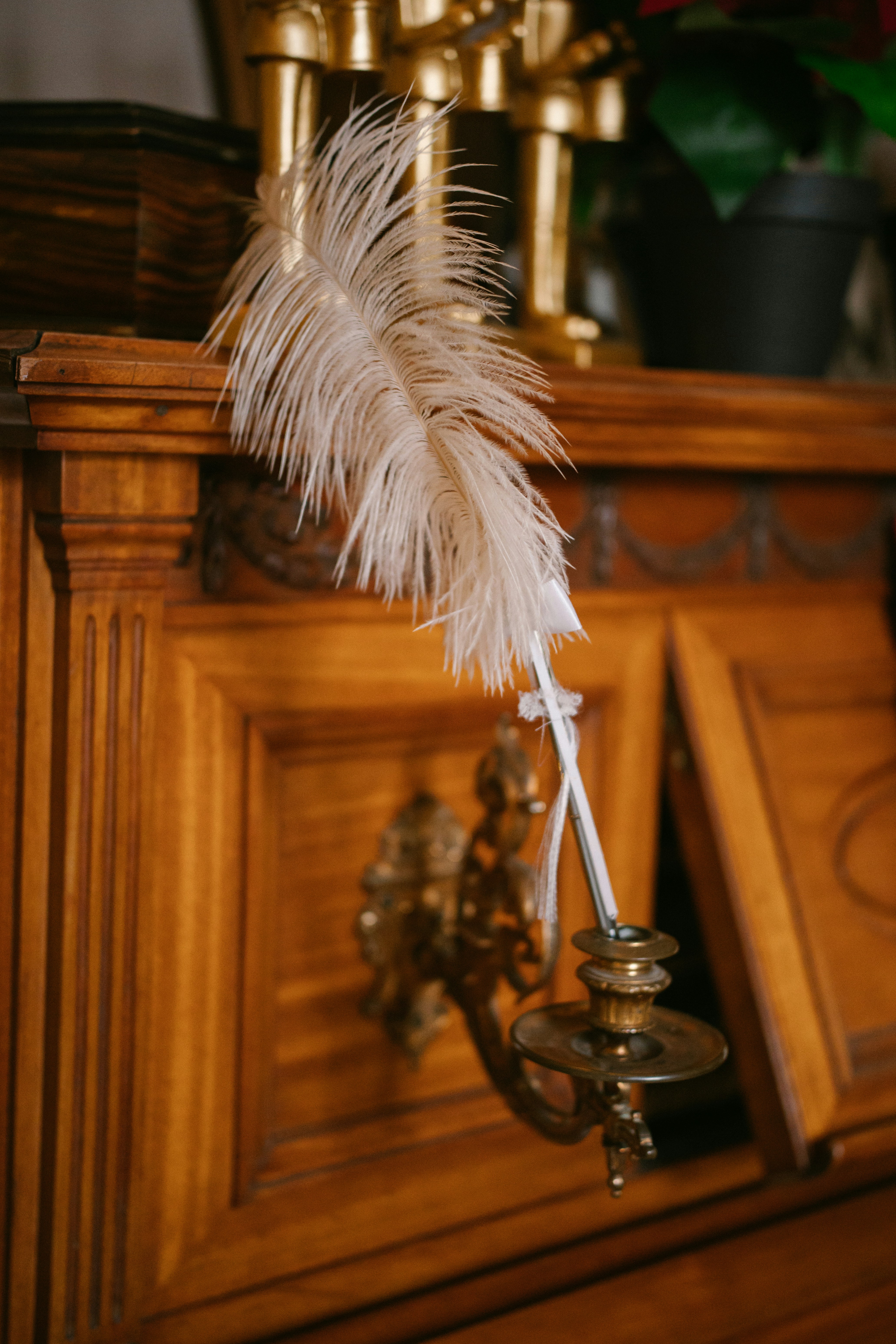 A feather hangs from a vintage candlestick.