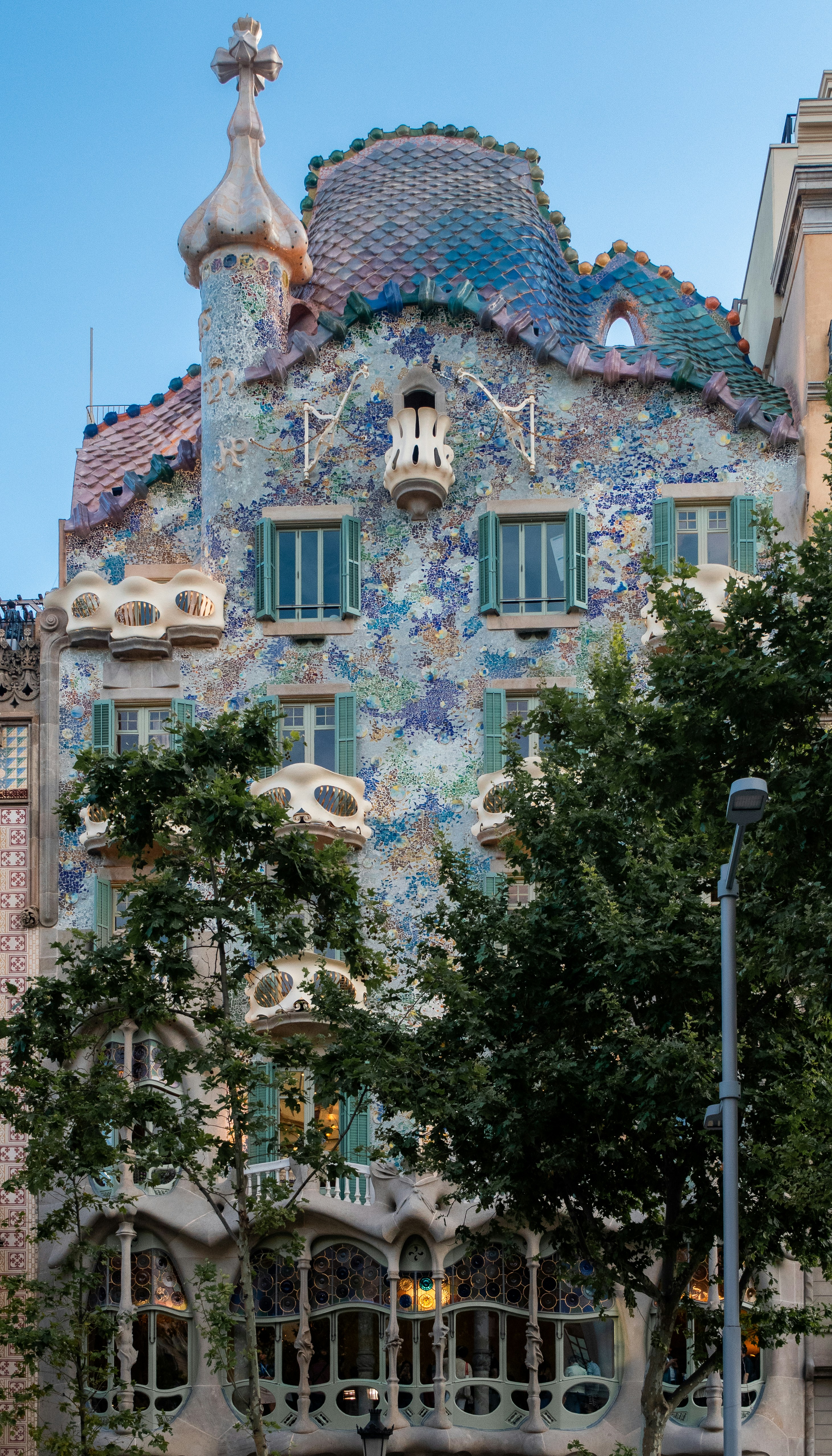 Colorful facade of casa batlló with trees in foreground