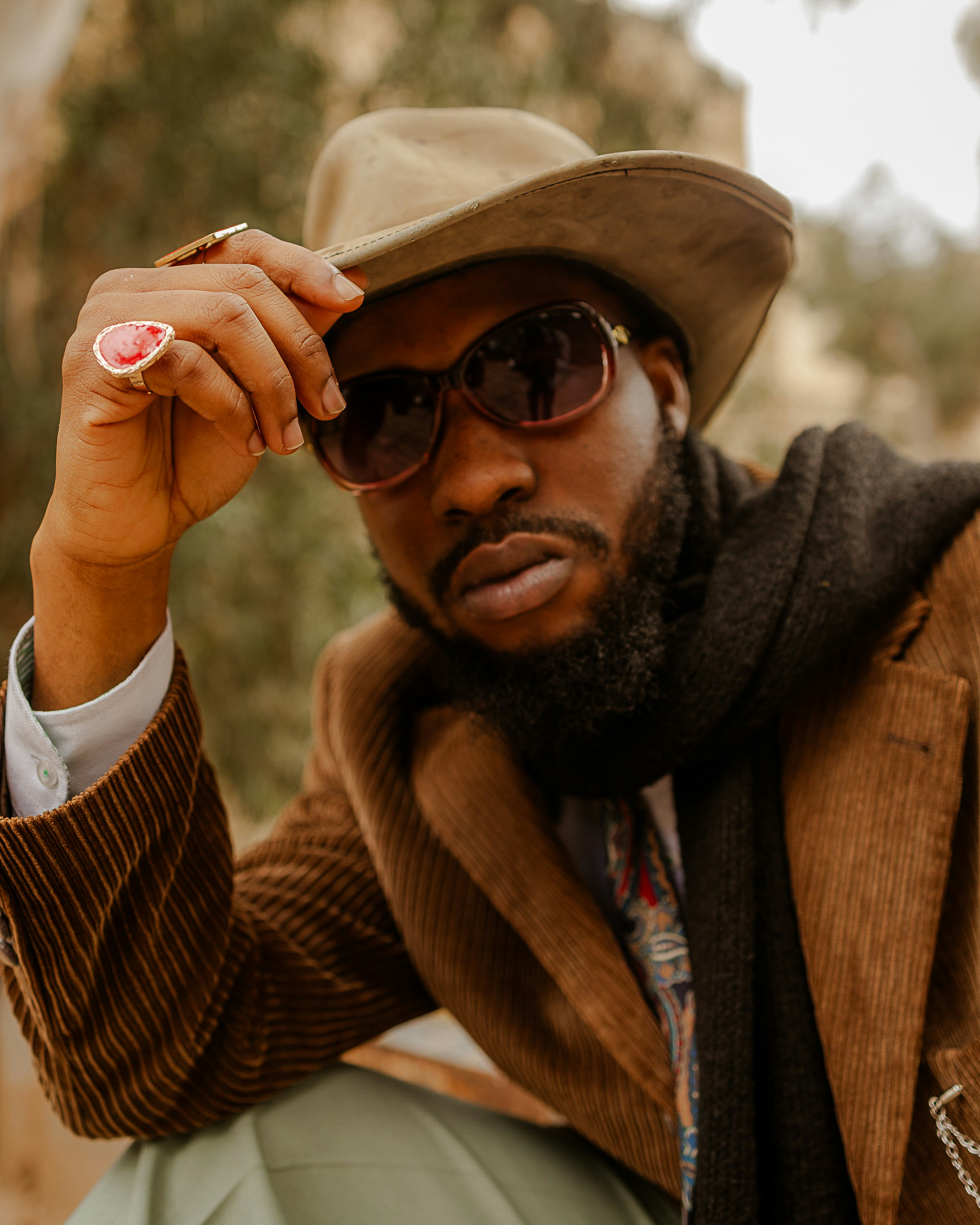 Man in cowboy hat and sunglasses poses outdoors