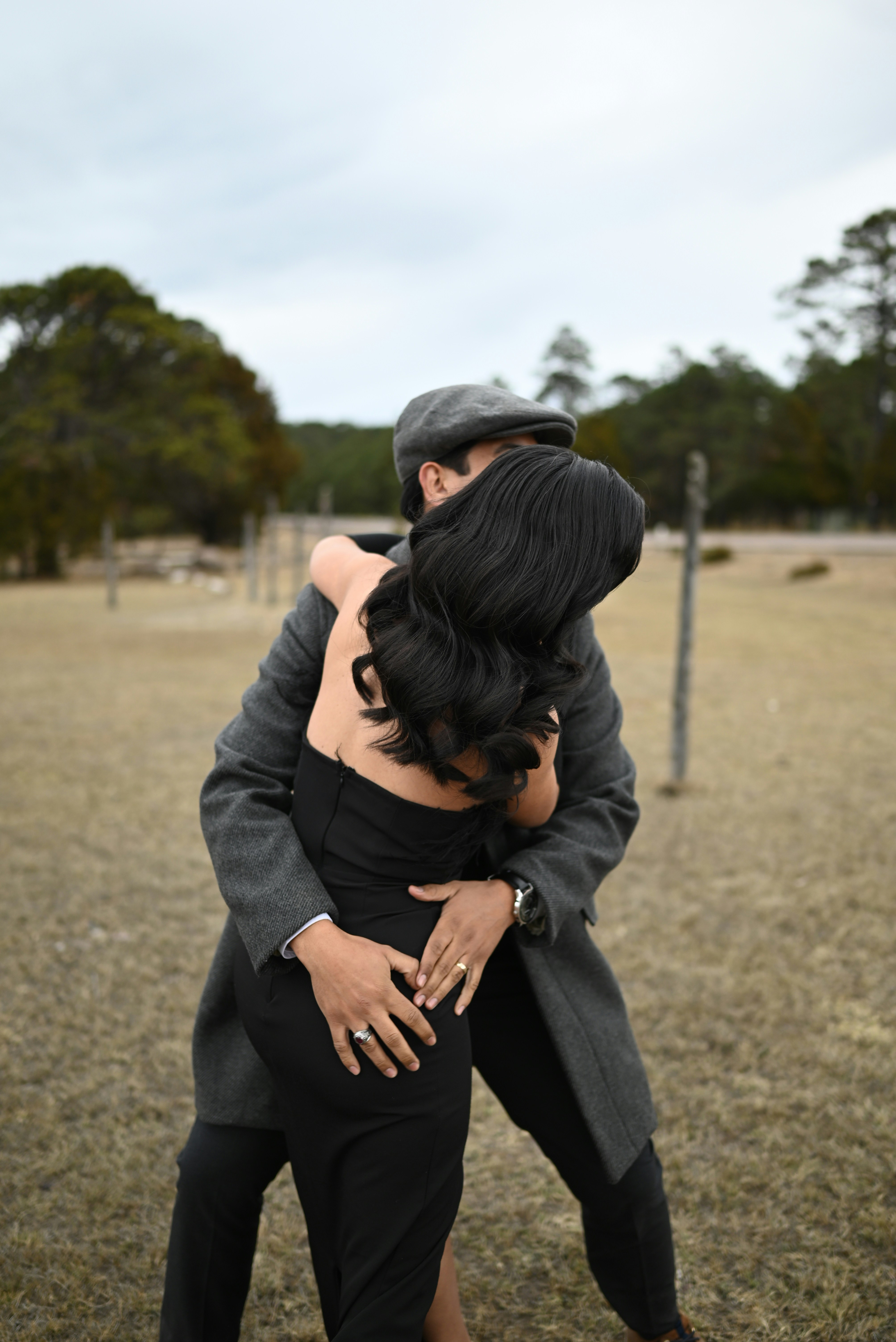 Couple embracing outdoors with a man wearing a hat