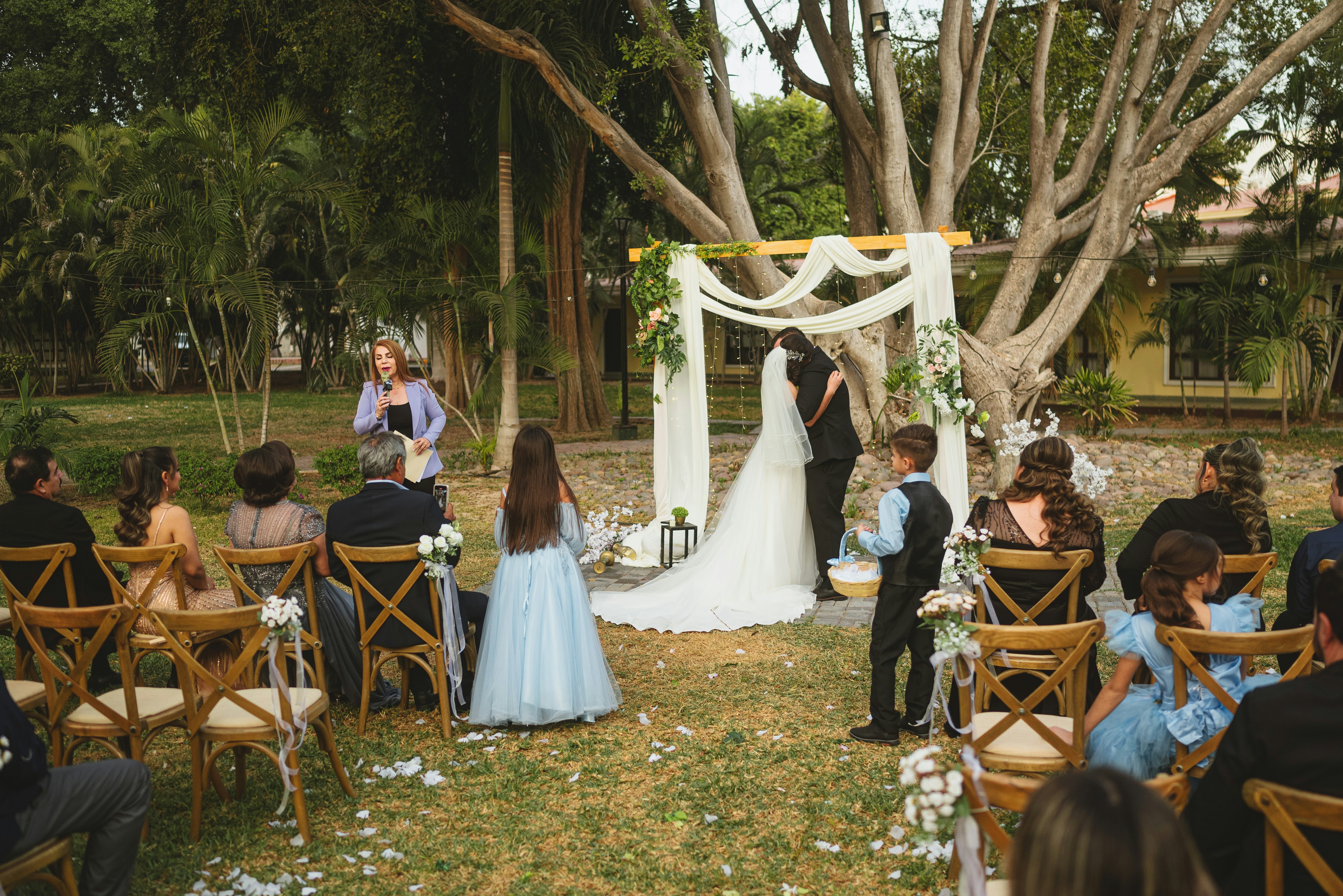 Une mariée et un marié s’enlacant sous une arche florale lors d’une cérémonie de mariage en plein air