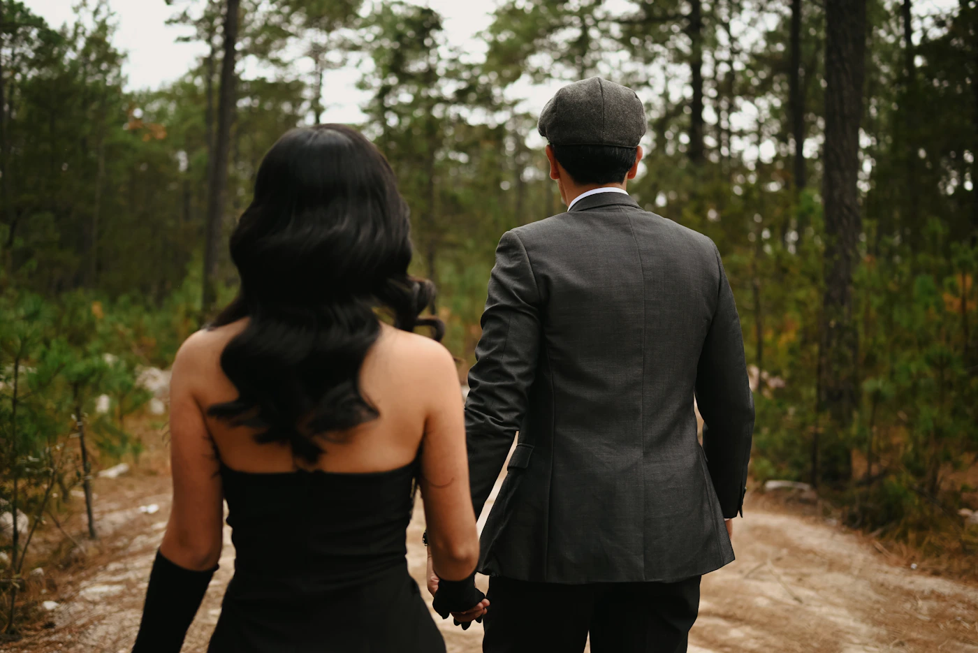 Elegant couple walking hand in hand together through green woodland