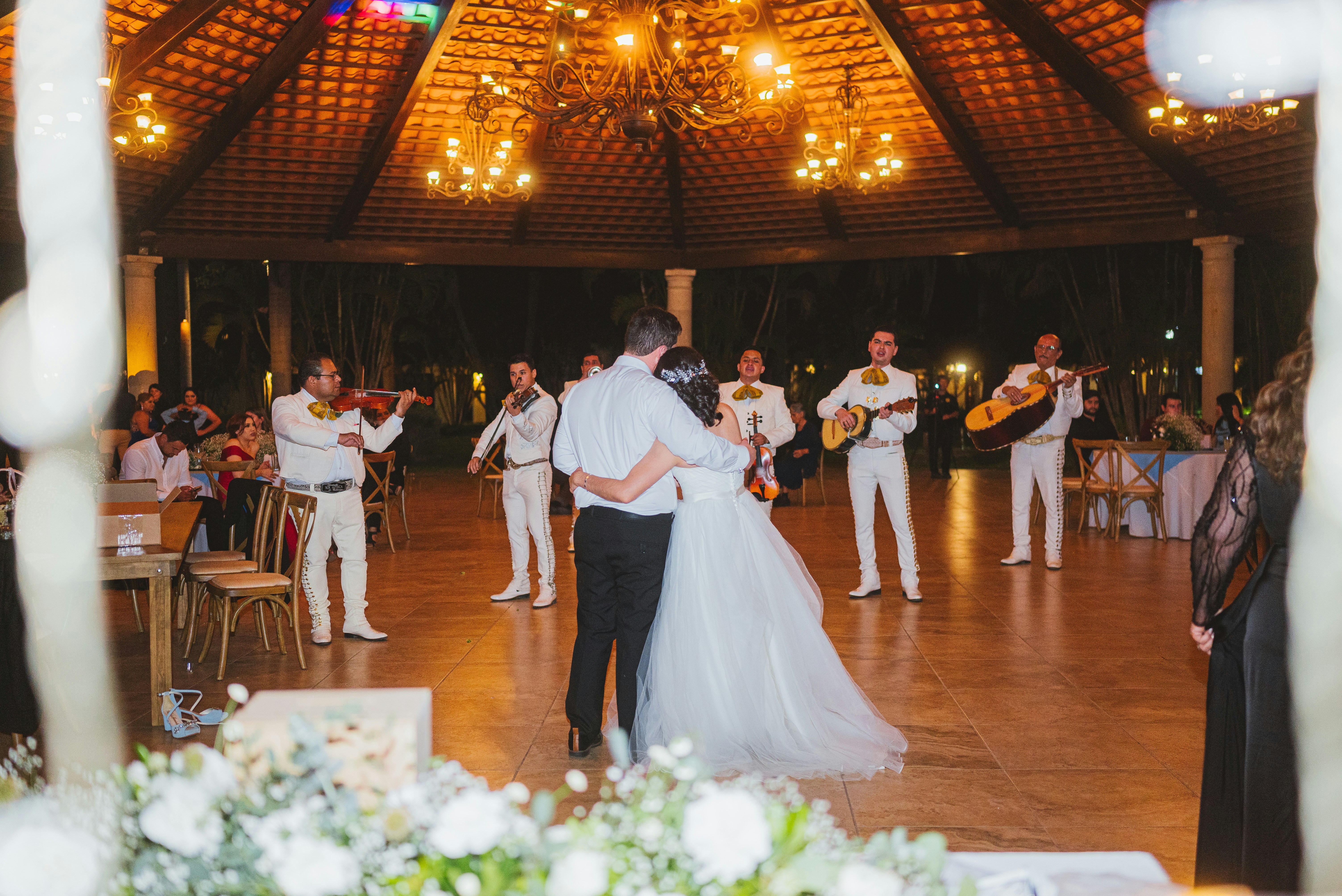 A mariachi band plays for a wedding couple dancing.