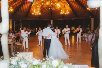 A mariachi band plays for a wedding couple dancing.