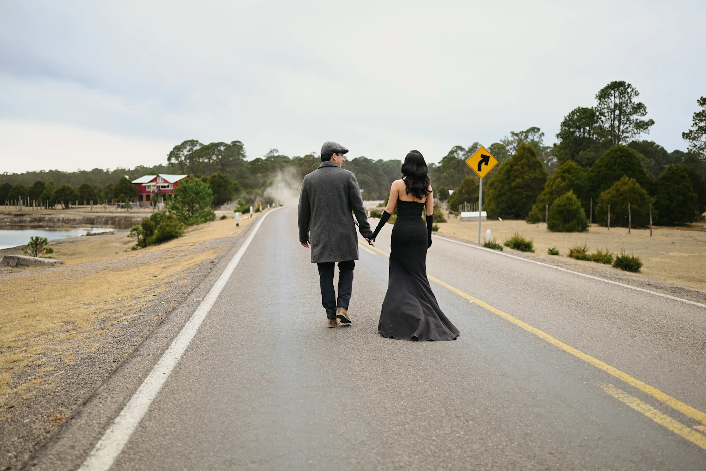 Couple in winter elopement attire at a Prince Edward County vineyard with the dormant winter vine rows and the frost-covered pastoral farmland of the County around them