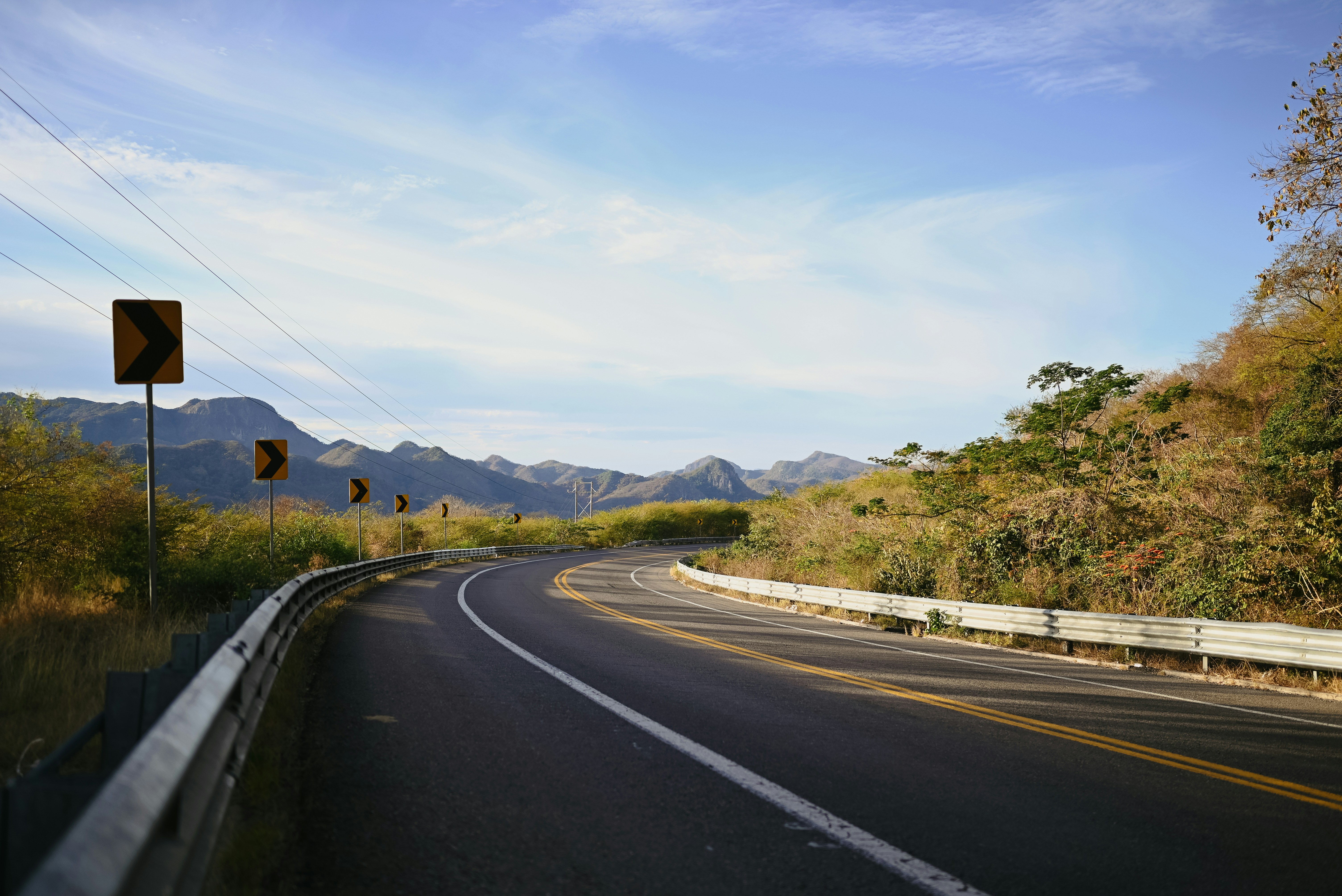 Curving road through a hilly landscape under a blue sky
