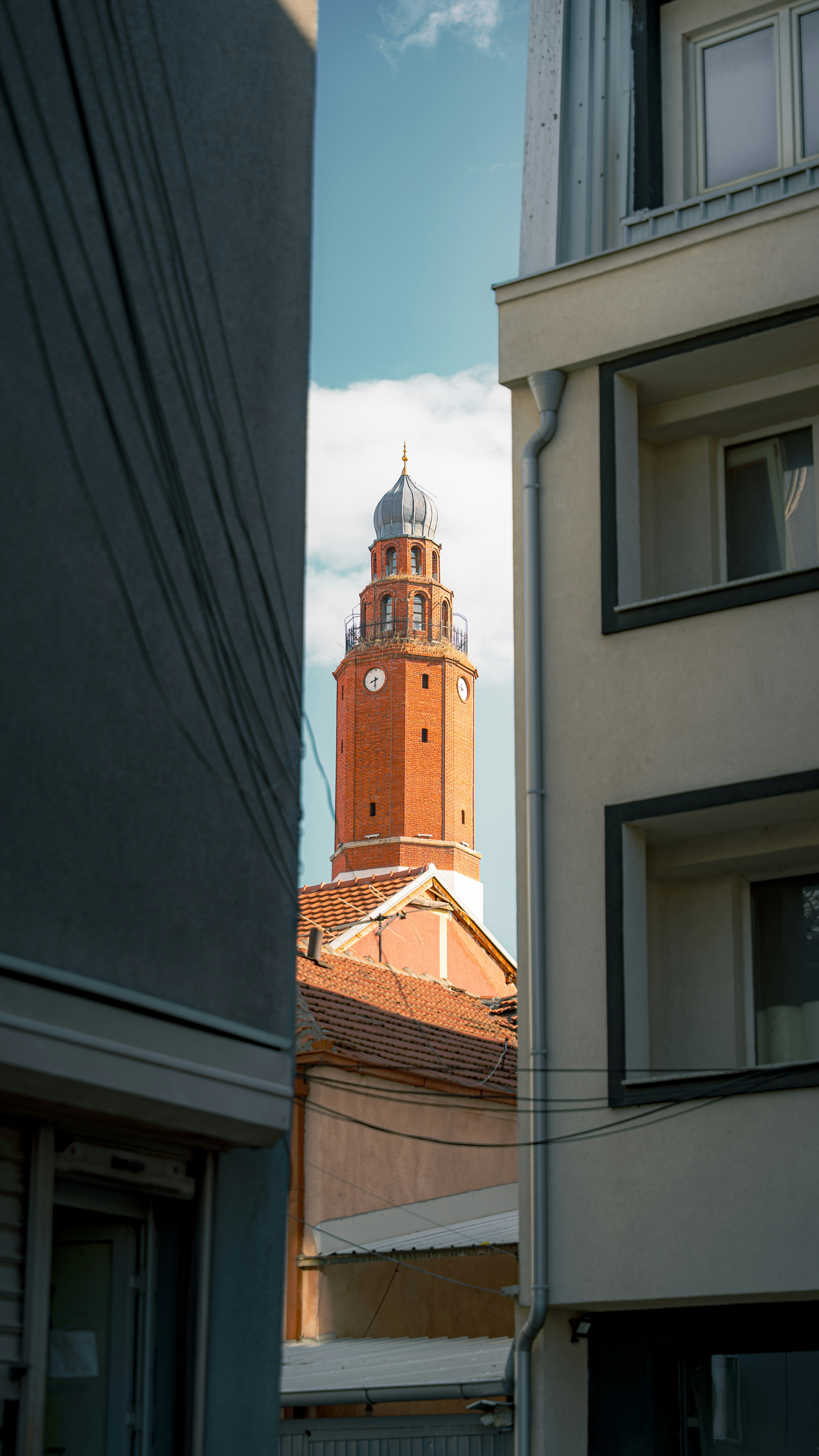 Brick clock tower between two buildings under sky