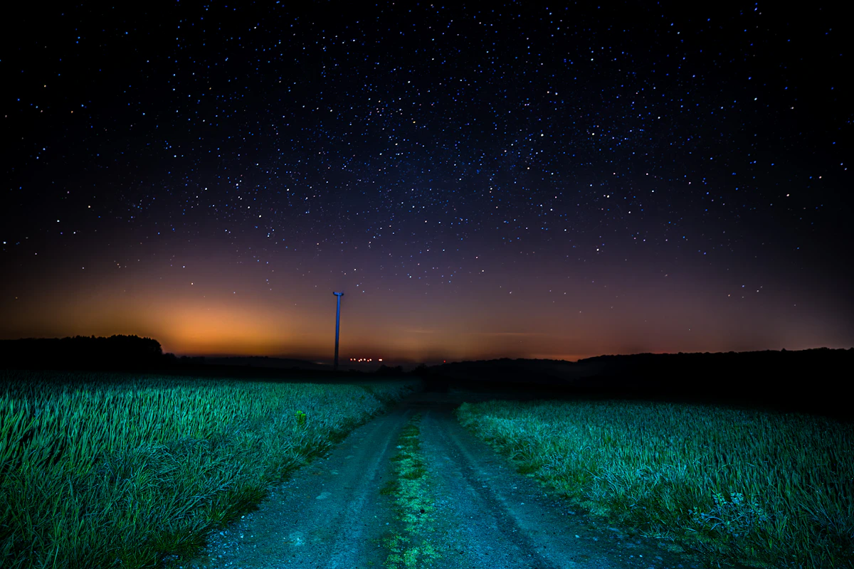 A glowing light hovering over a dark rural field at night