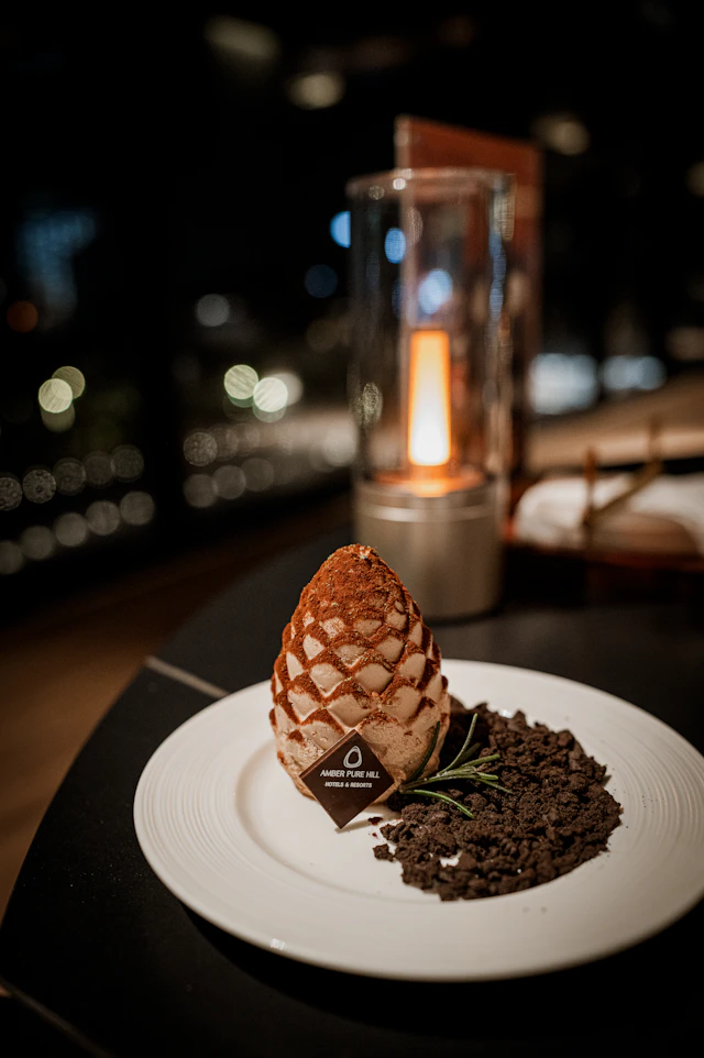 A dessert shaped like a pine cone by candlelight