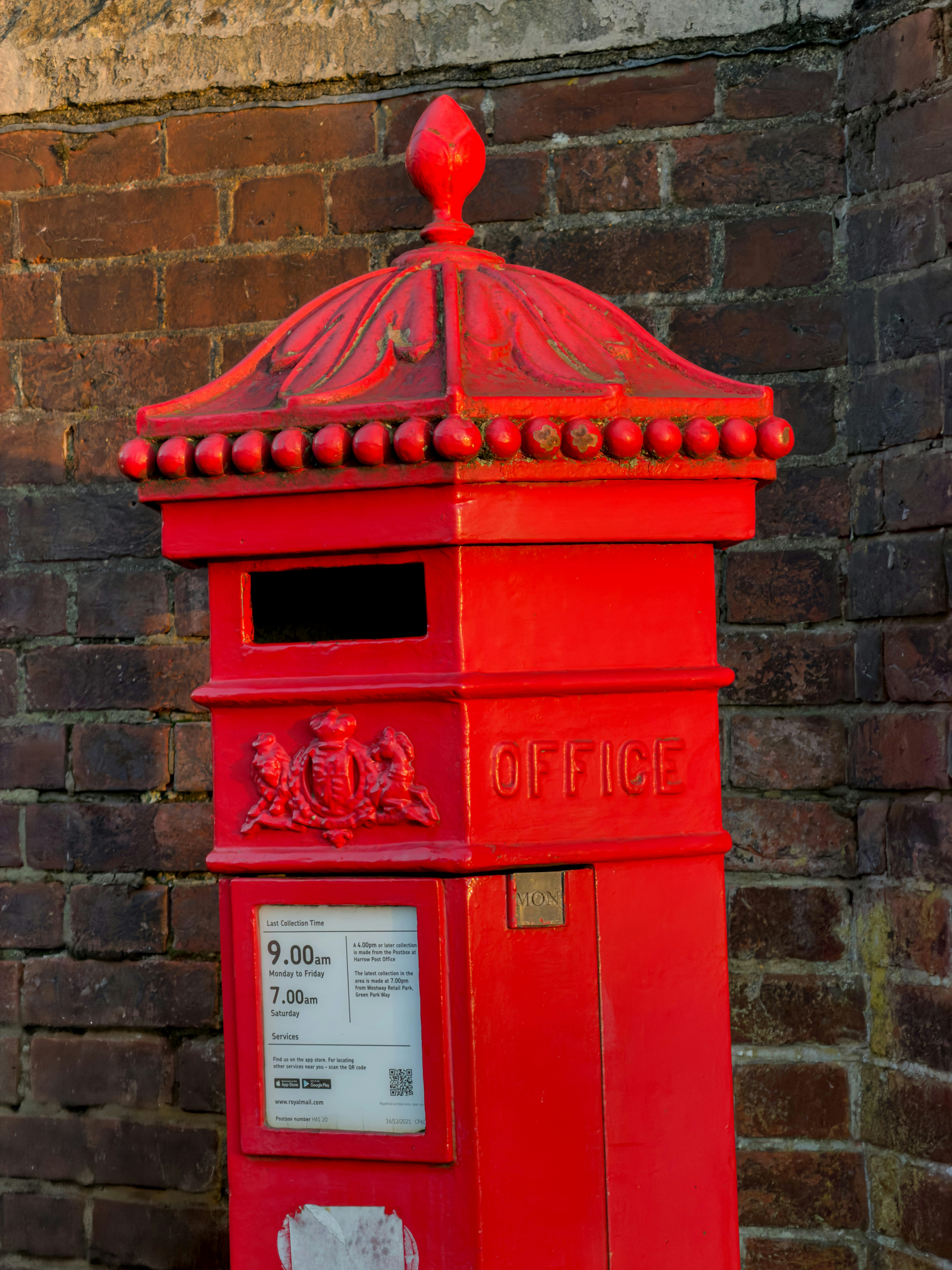 A bright red vintage post box against a brick wall.