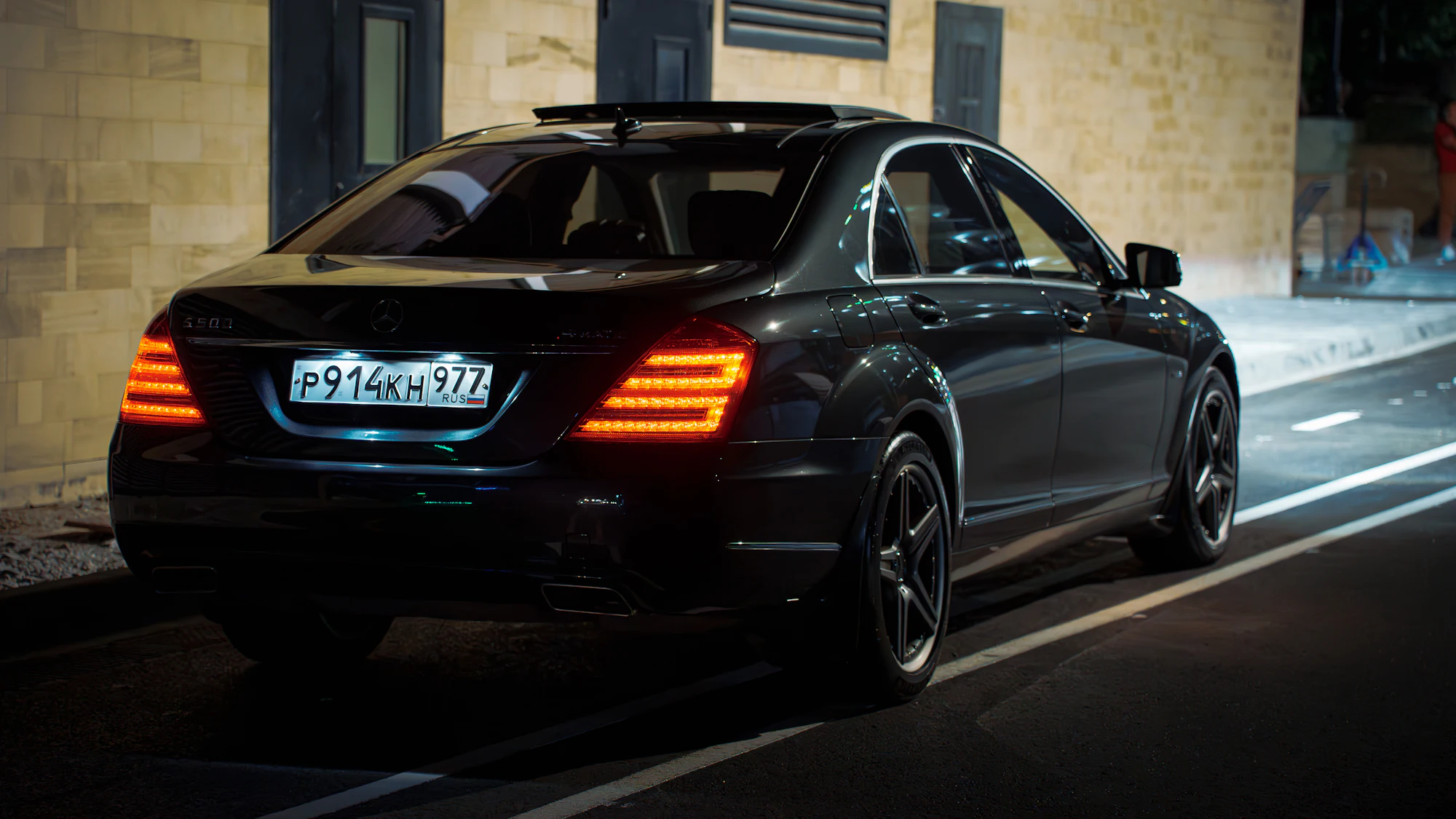 Black luxury sedan parked on a city street at night