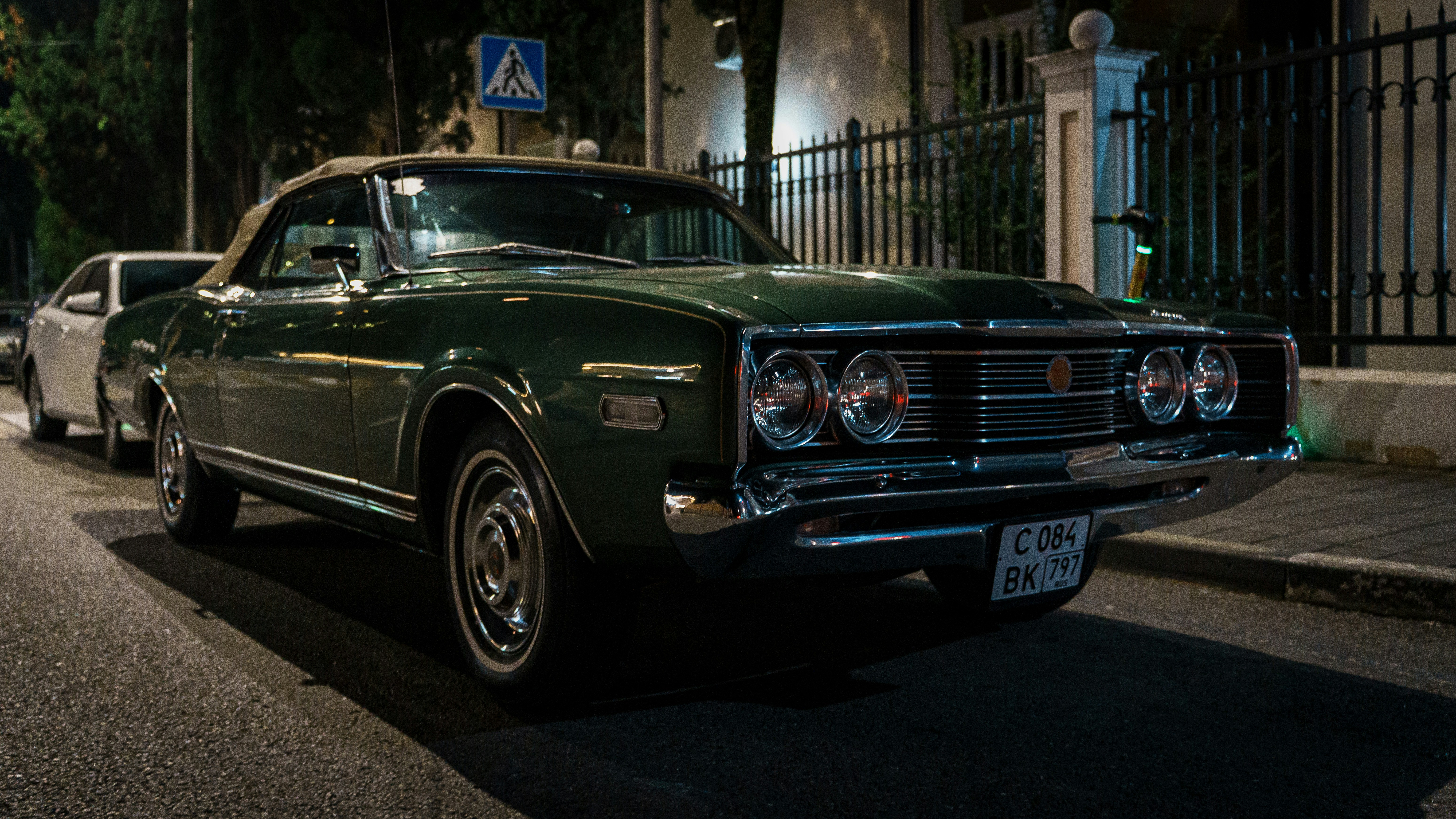 A vintage green car parked on a street at night.
