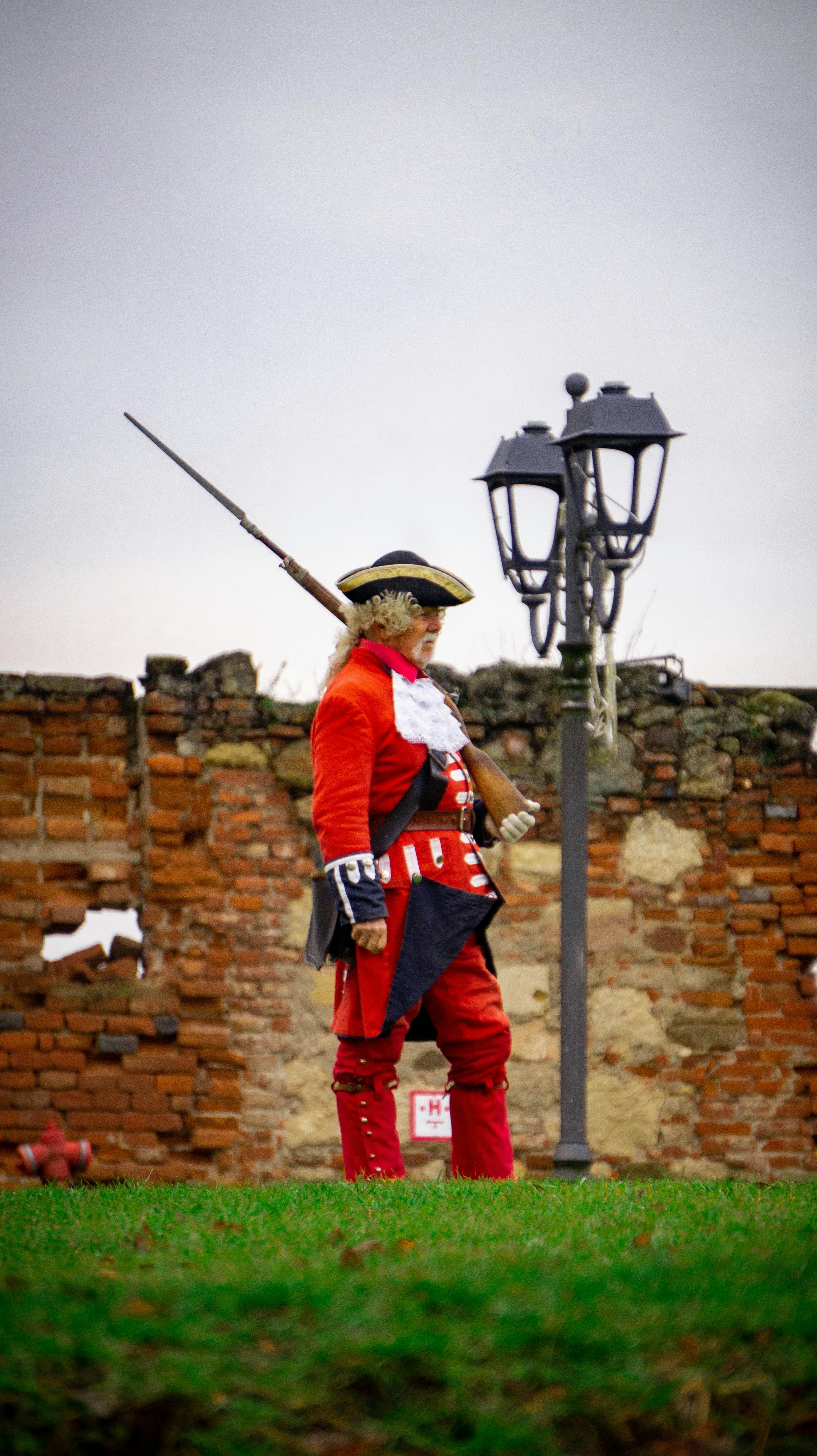 Man in historical red uniform with musket and hat.