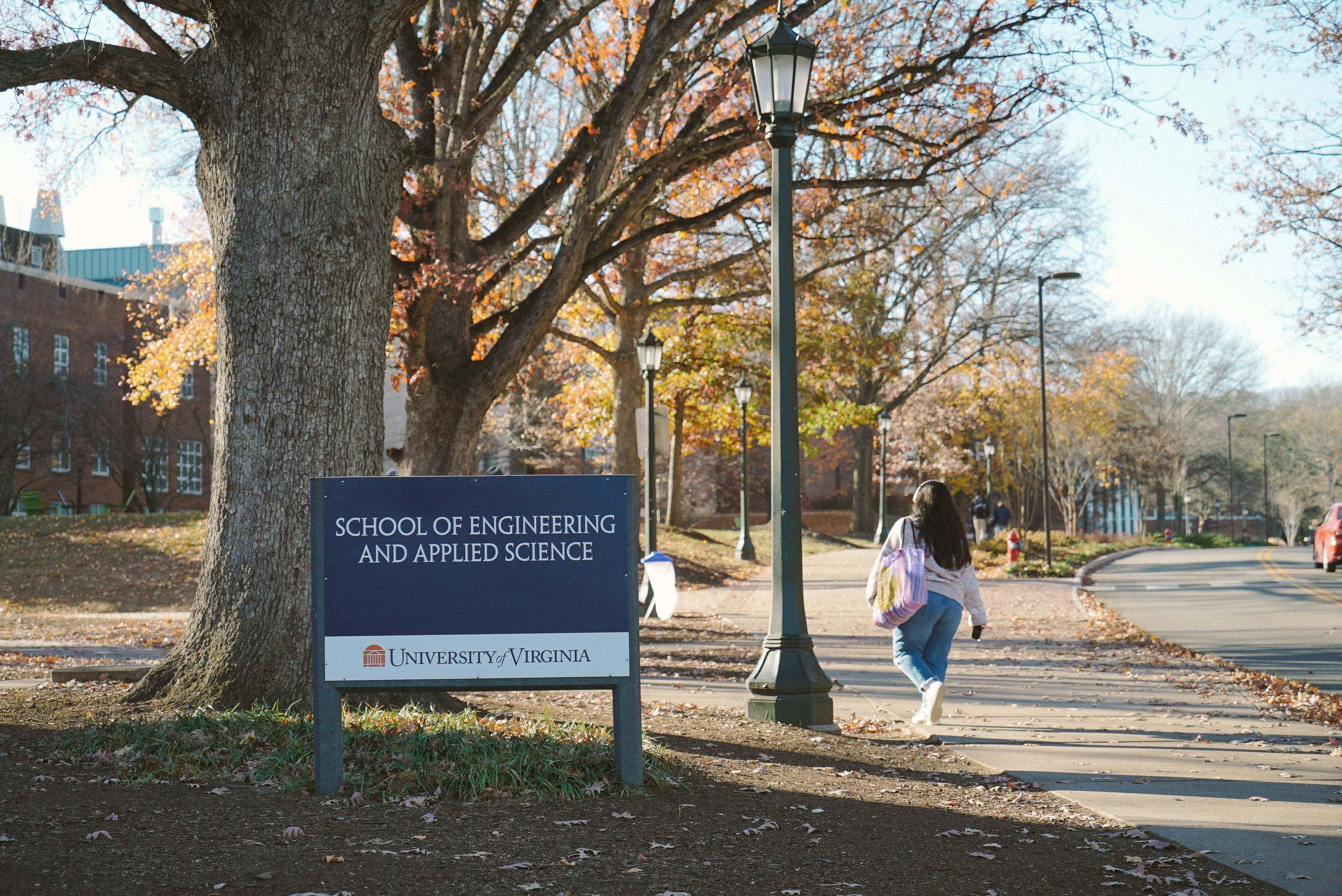 A student walks past a sign for school of engineering.