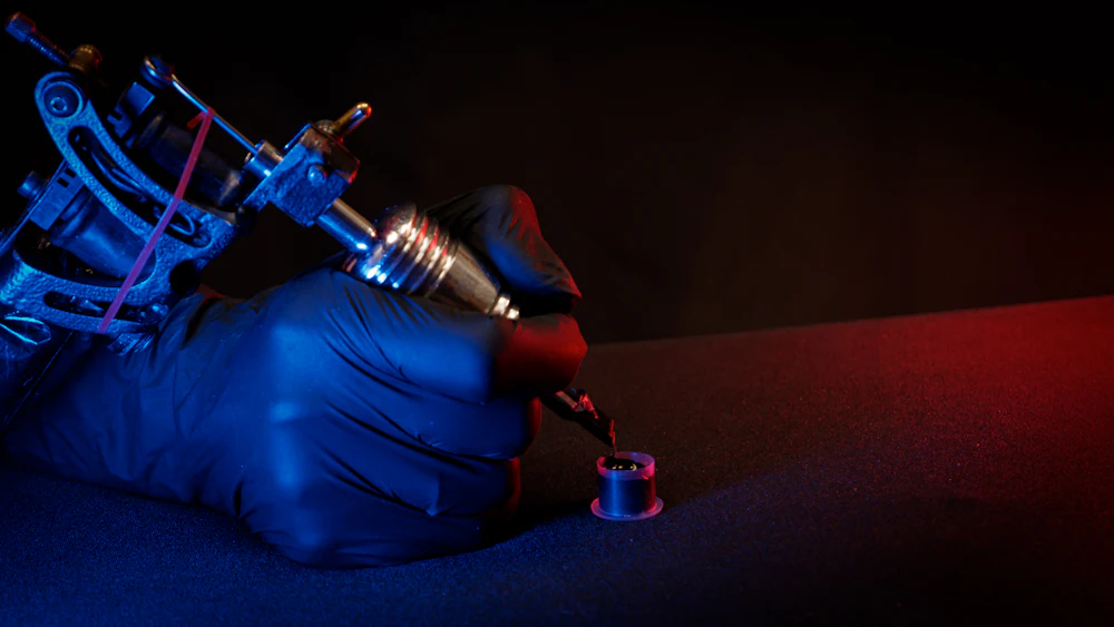 A hand holding a tattoo machine mid-stroke.