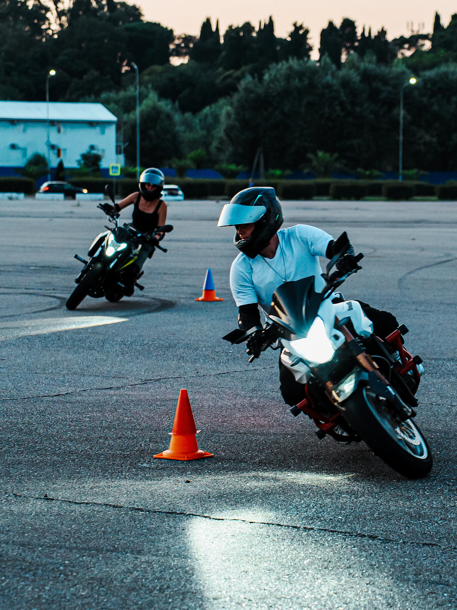 Two learner riders practising slow turns around orange cones