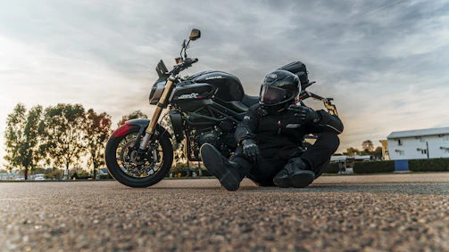 Motorcyclist in full gear sits by bike at sunset