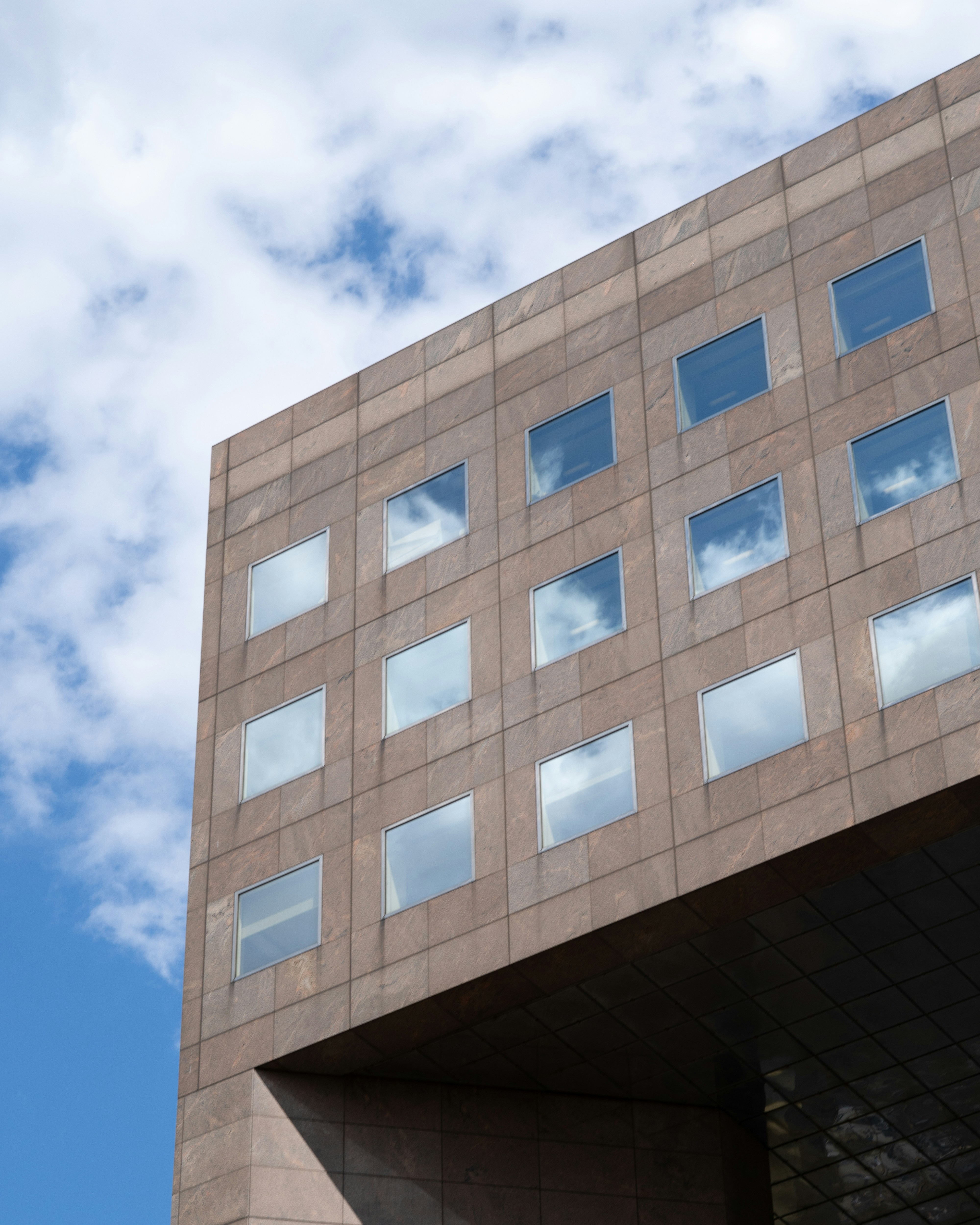 Modern building facade with reflective windows against sky