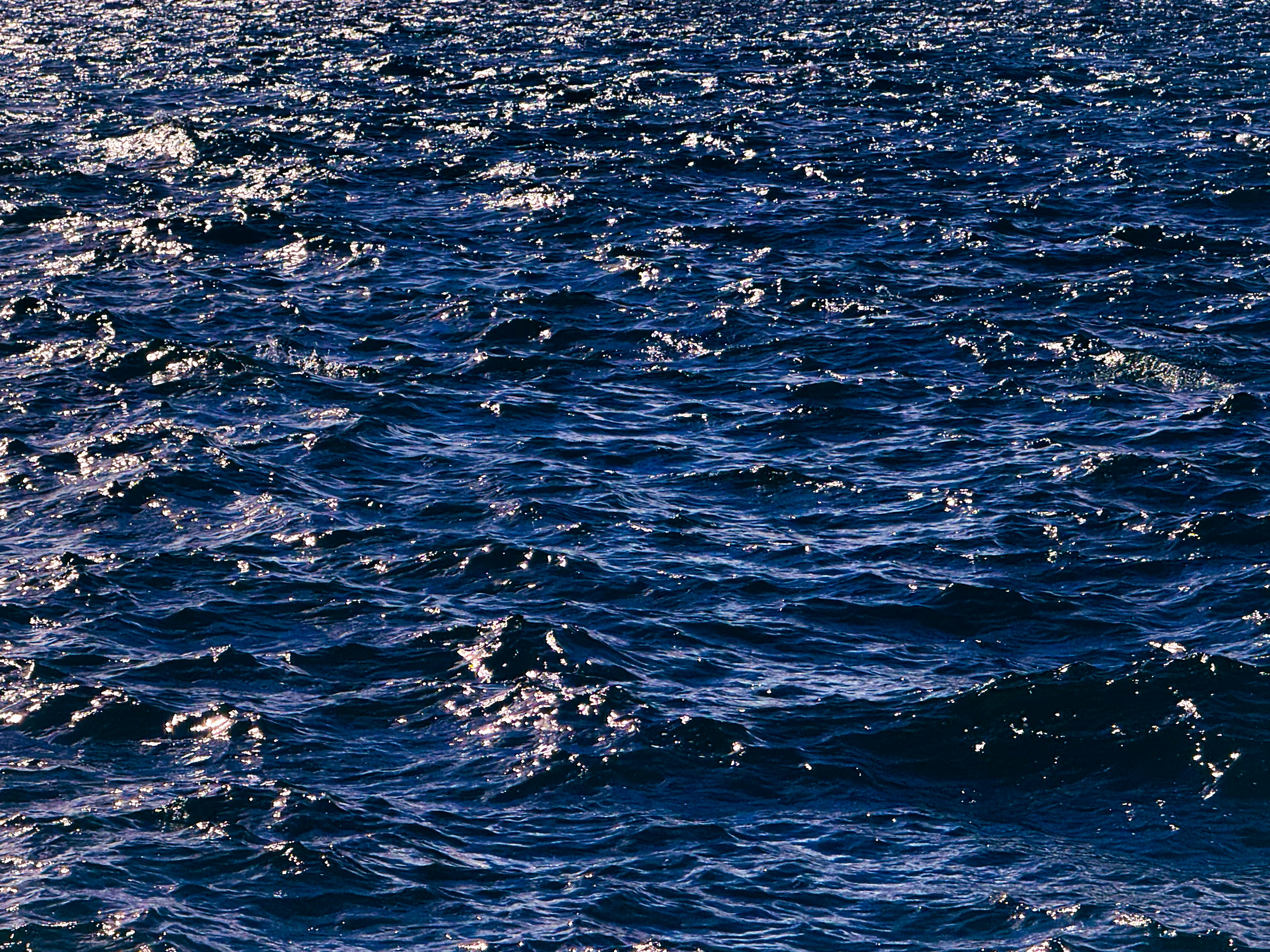 Dark blue ocean waves with sunlight glinting