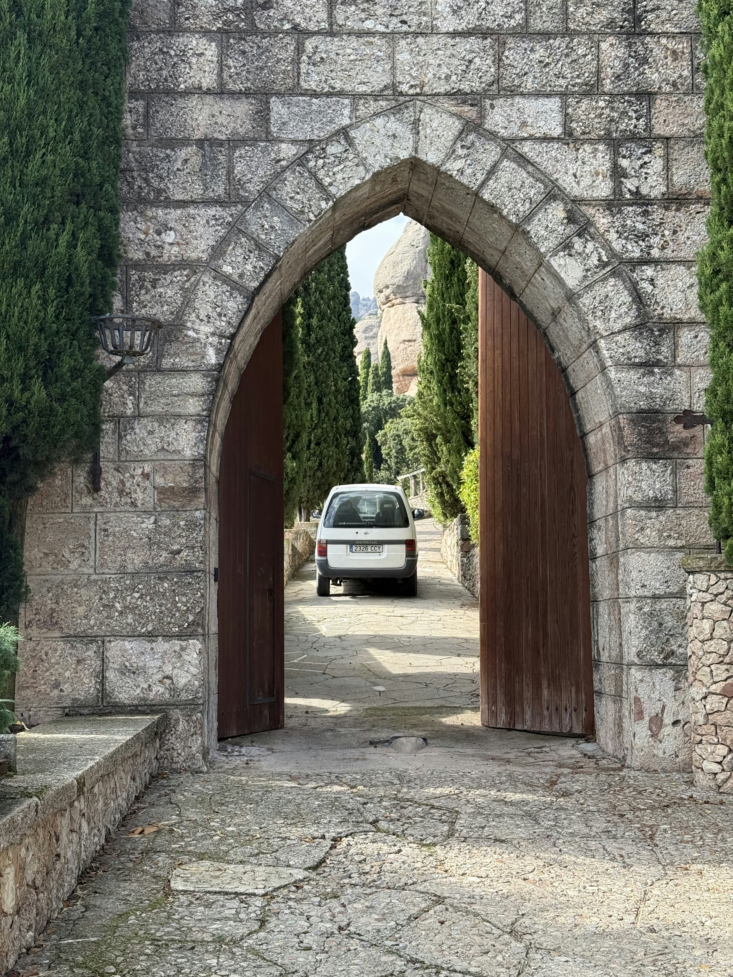 White car parked in an arched stone gateway.