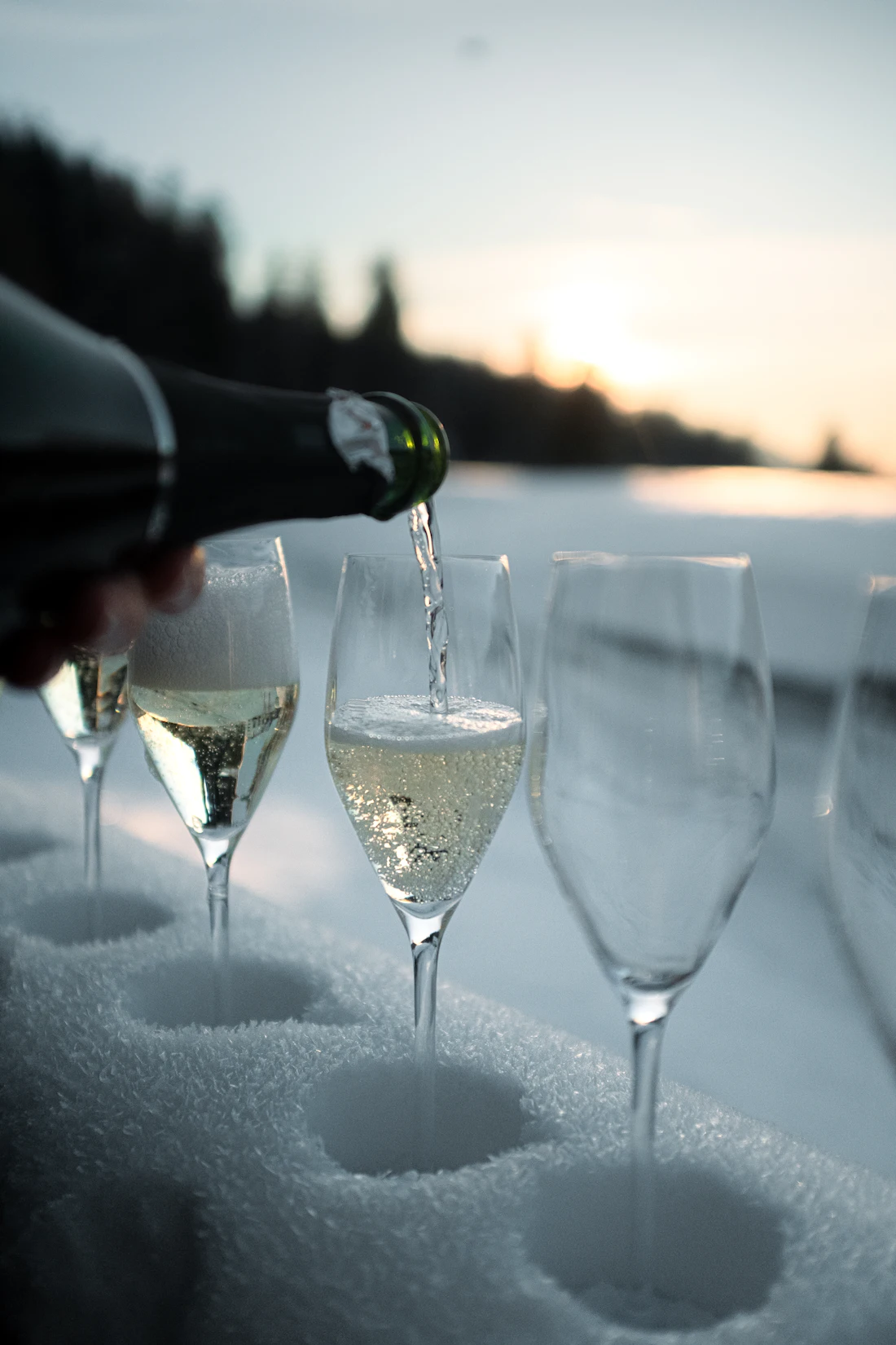Champagne wordt ingeschonken in glazen in de sneeuw
