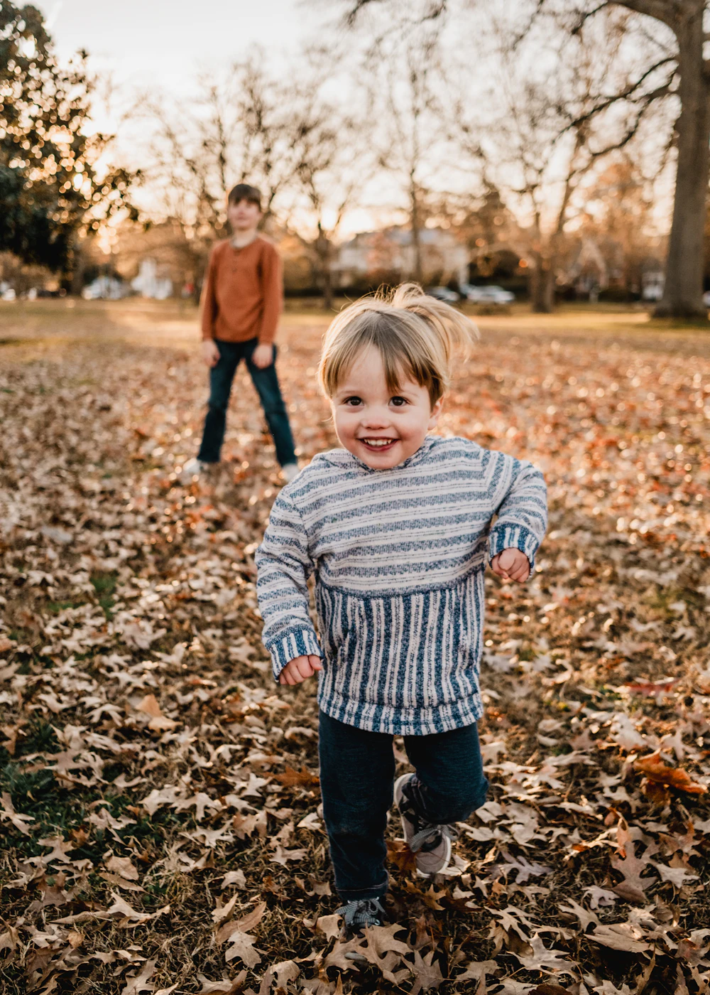 Two kids playing in autumn leaves