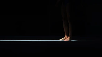 A person's bare feet illuminated by a single light beam.