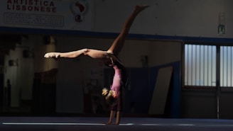 Gymnast performing a handstand on a blue mat.