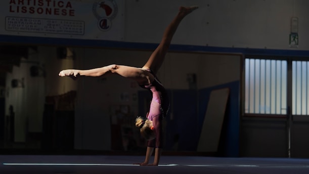 Gymnast performing a handstand on a blue mat.