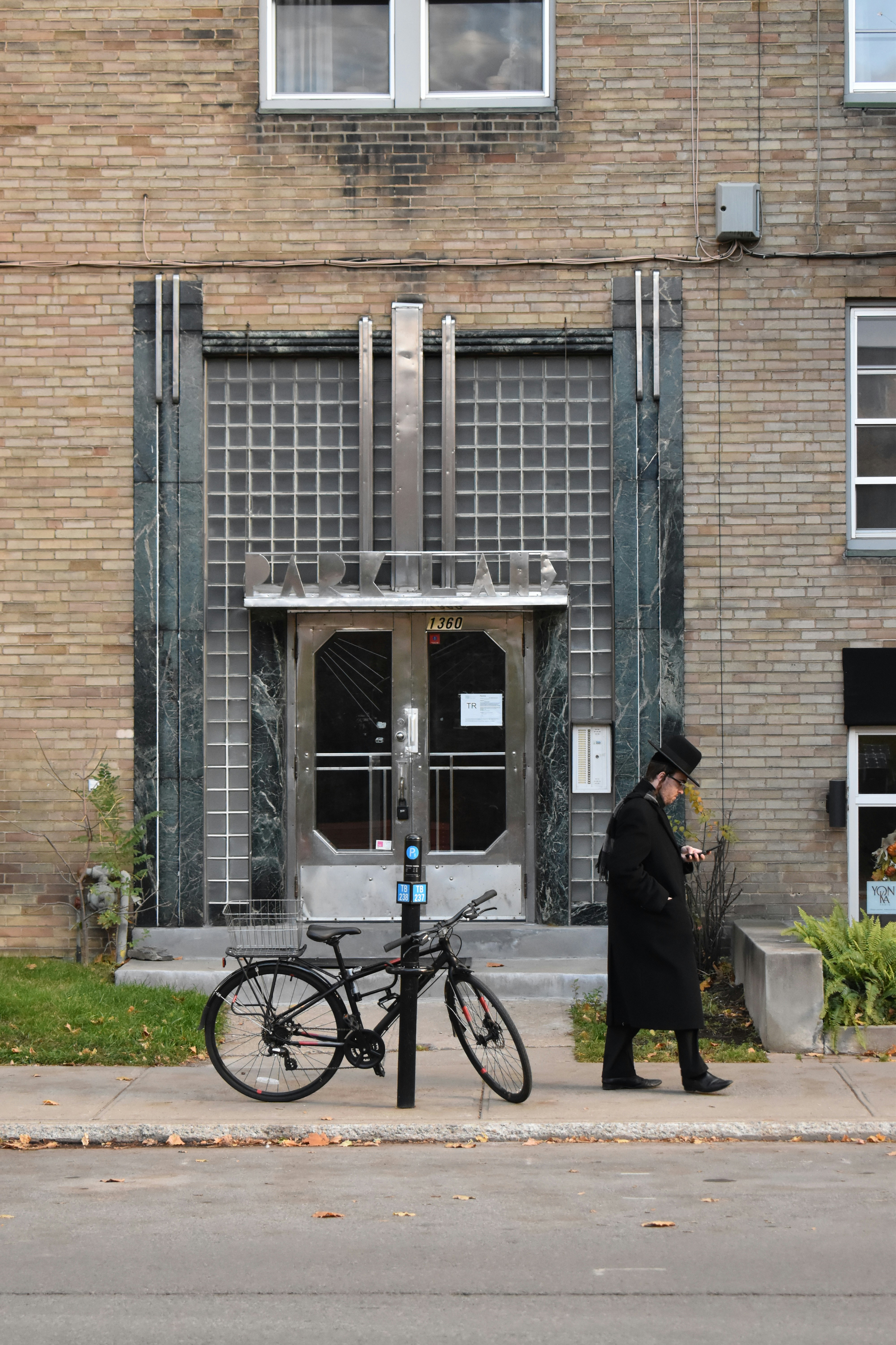 Mann im schwarzen Mantel geht am Eingang des Gebäudes vorbei