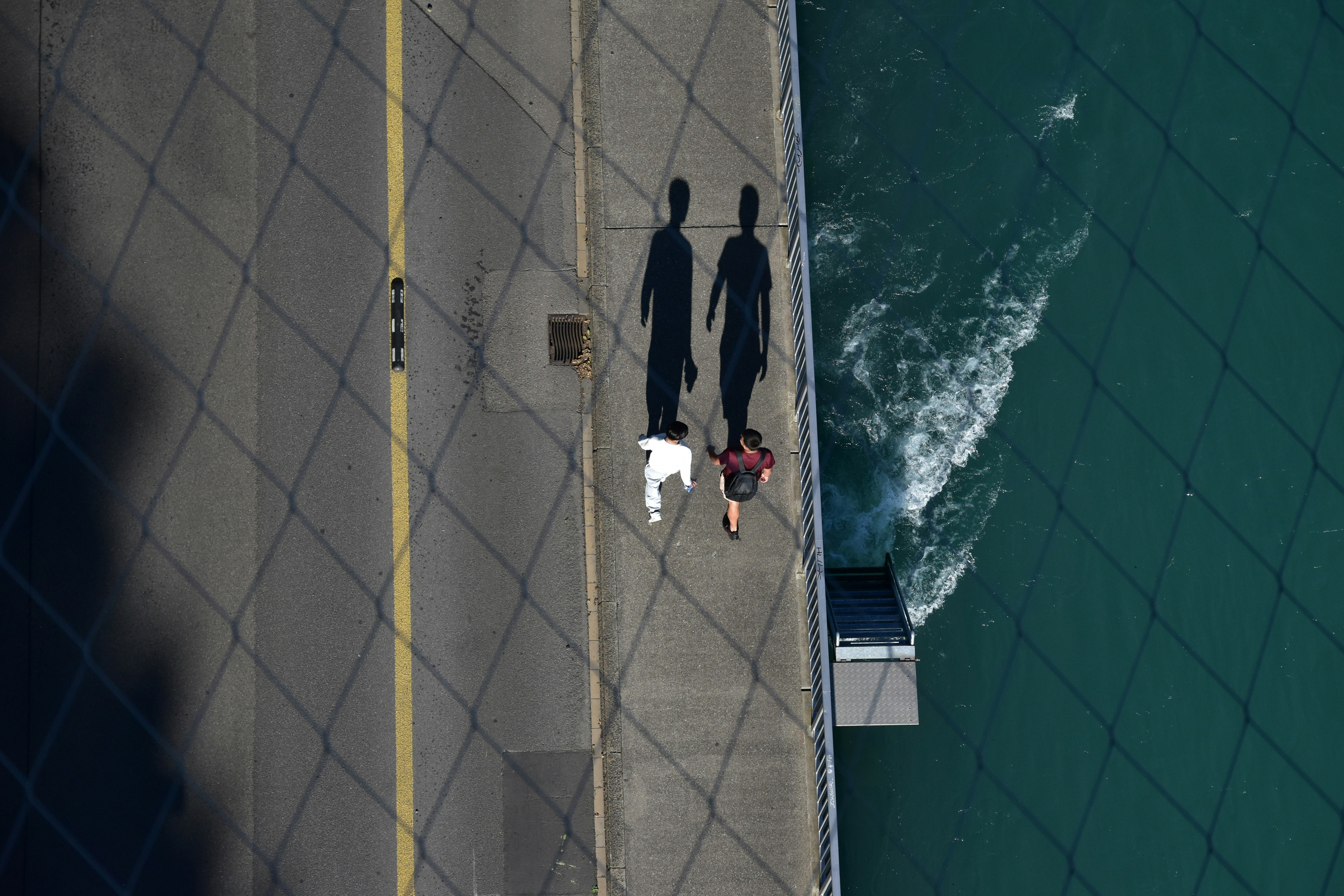 Two people walking on a bridge above water
