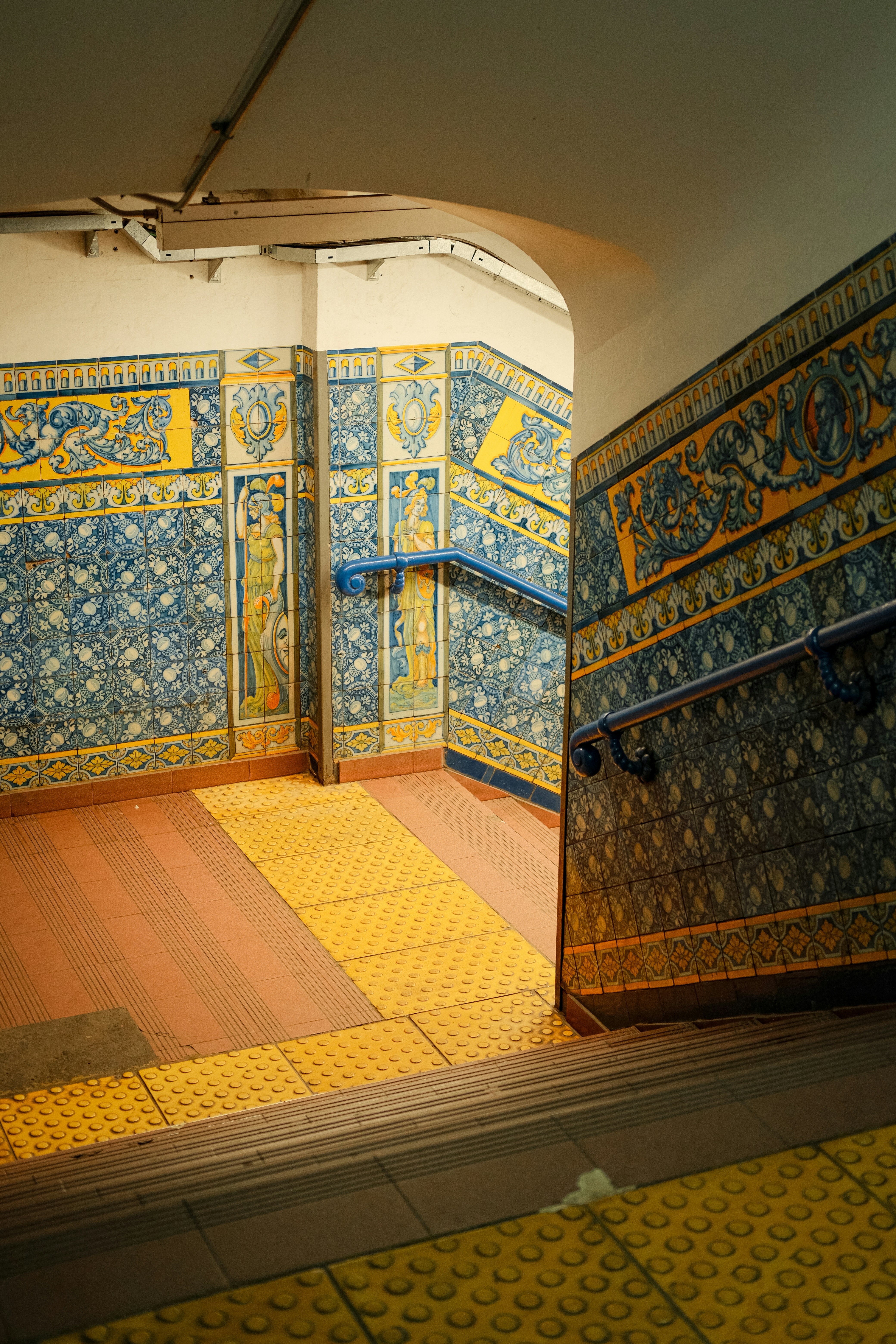 Ornate tiled subway station staircase with yellow accents