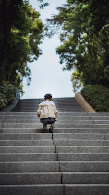 Child climbing stone stairs towards trees