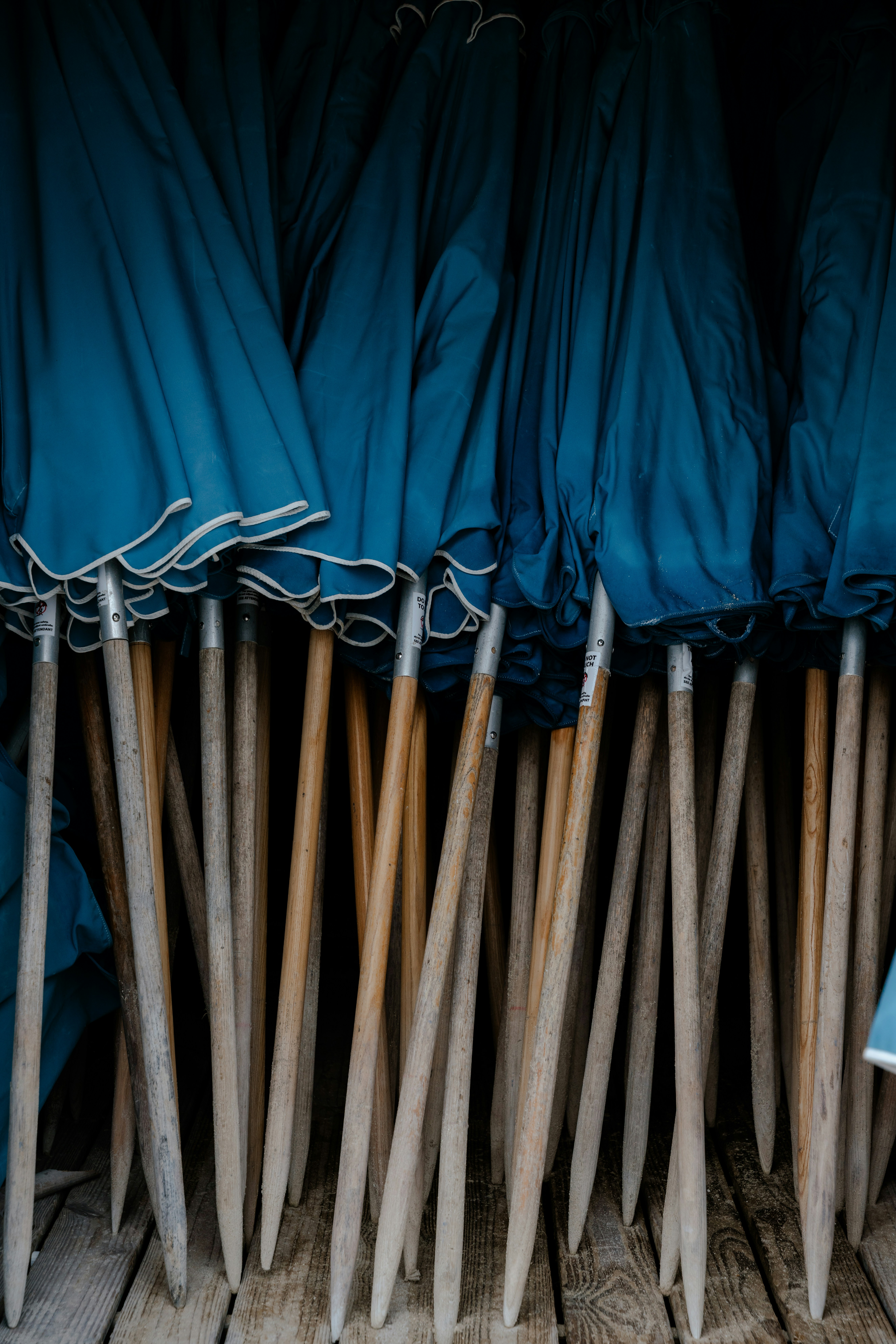 Blue beach umbrellas stacked together on wooden planks