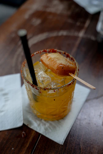 Yellow cocktail with ice and fruit garnish