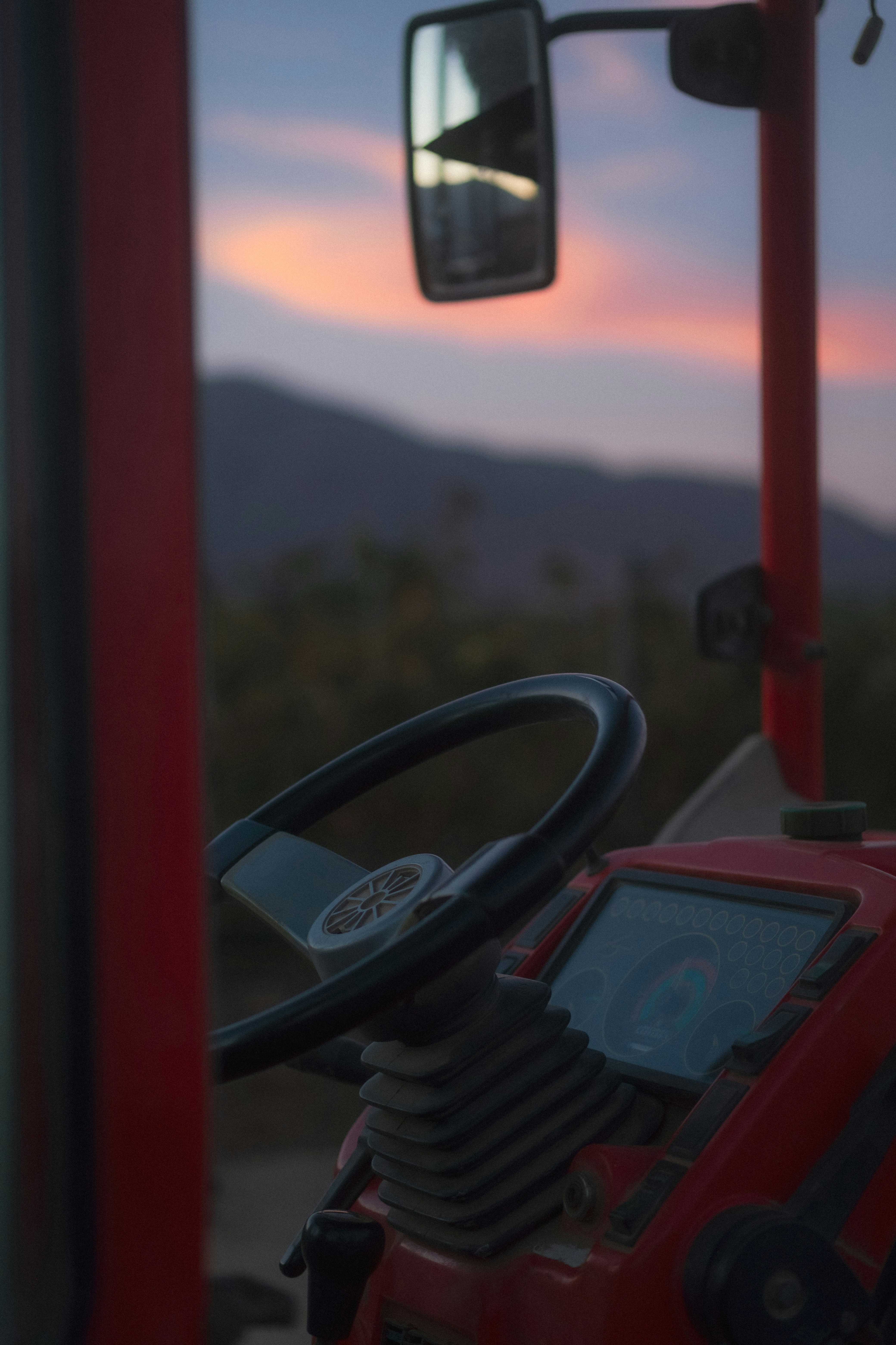 Red tractor steering wheel at sunset