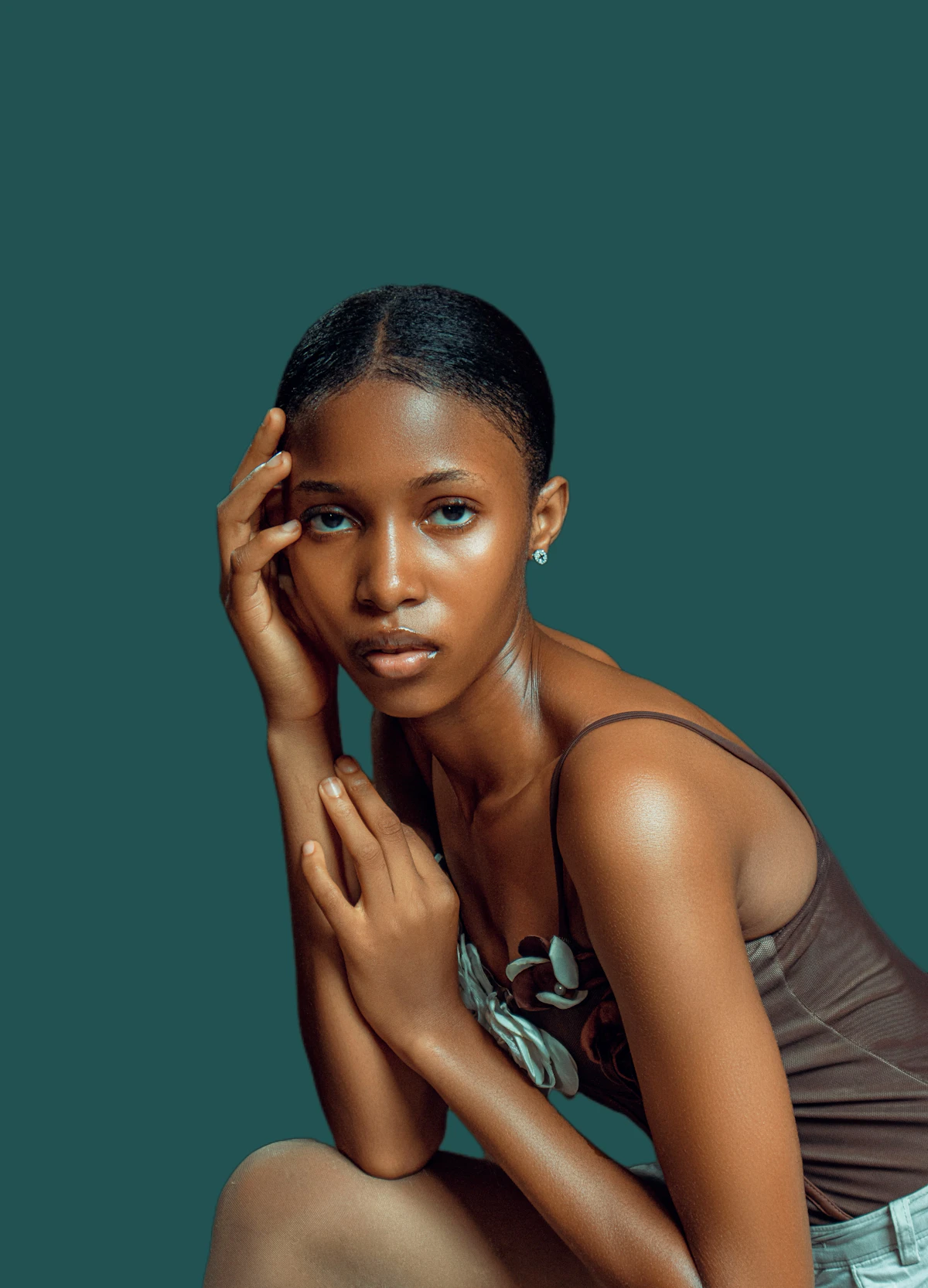 Minimal beauty portrait against a rich teal backdrop