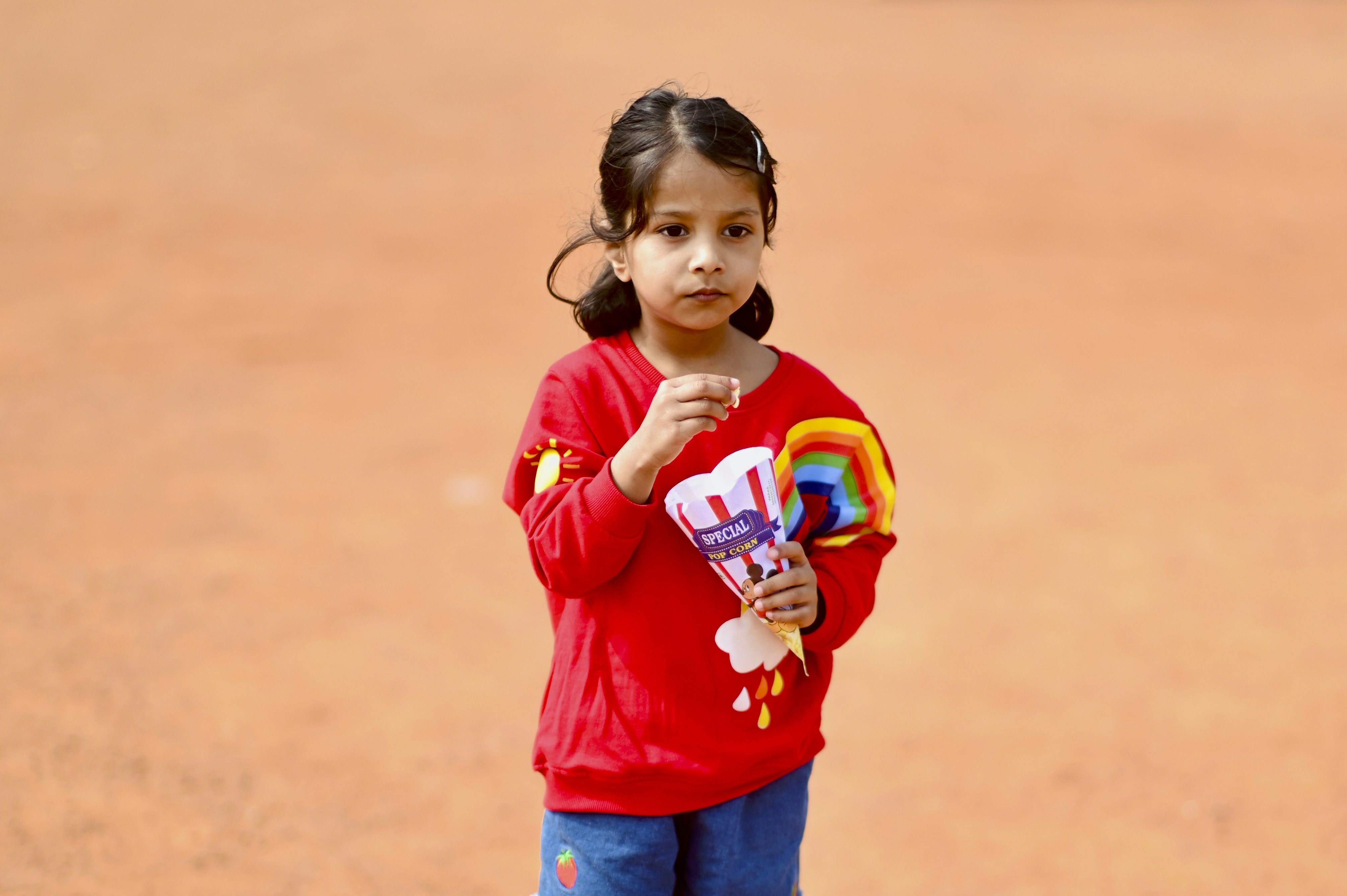A young girl in a red shirt holds candy.