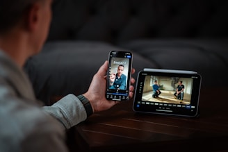 Man video calling on phone next to digital monitor