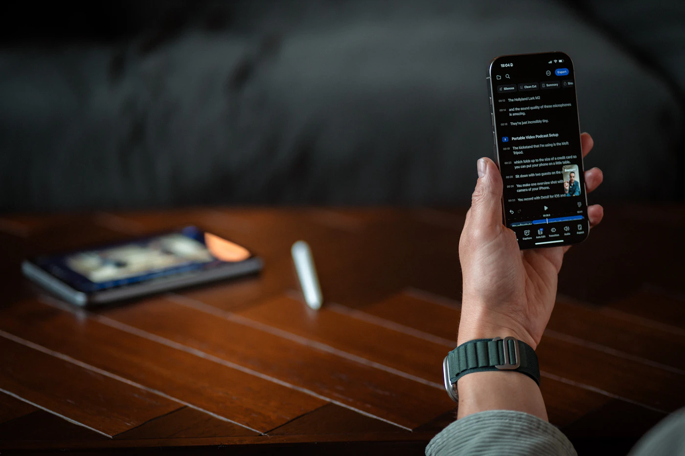 Person holding a smartphone in a dark workspace